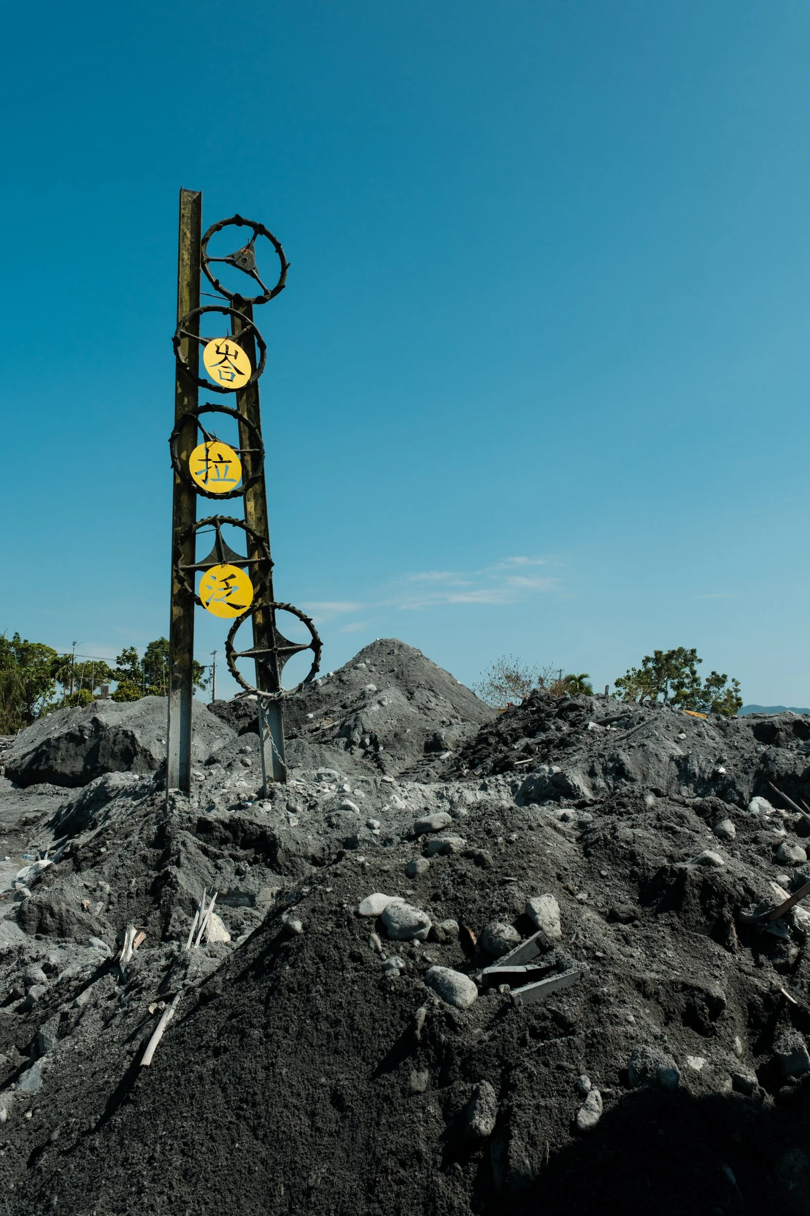 A color image of a community sign poking out of the mud and rubble on Buddha Street in Guangfu.