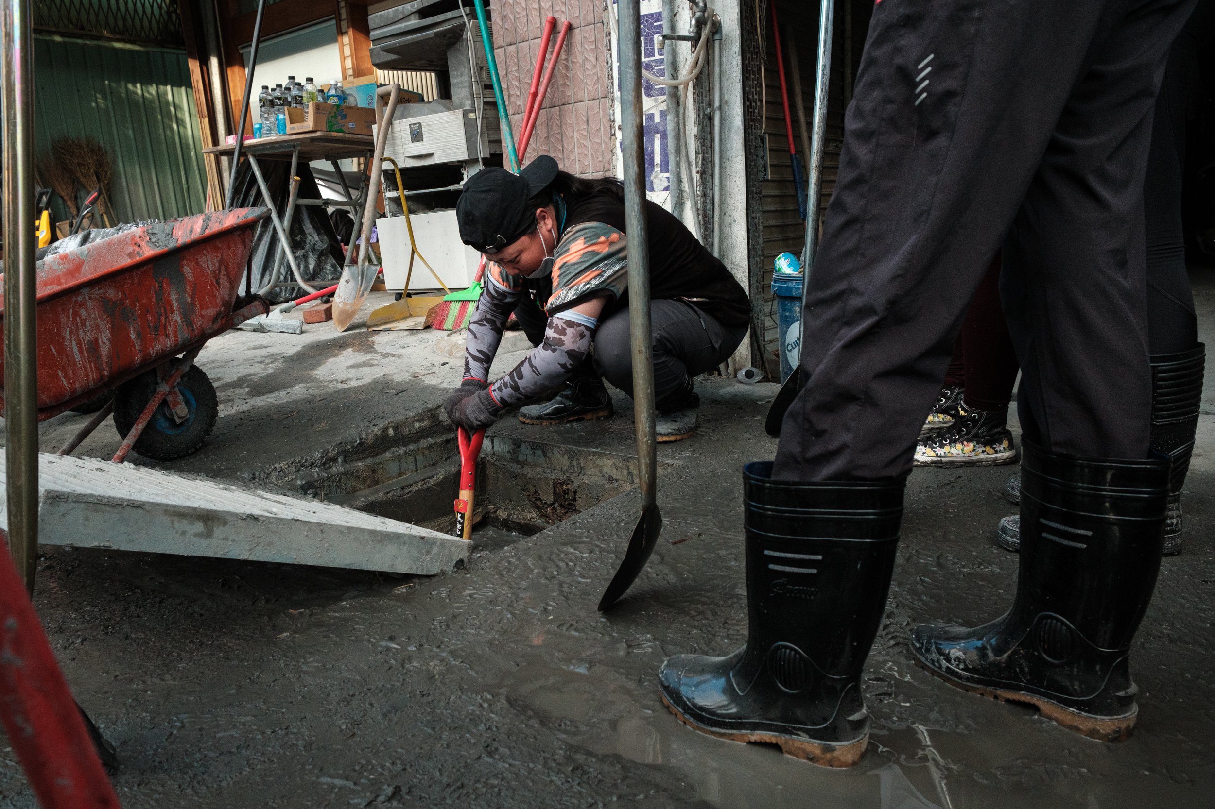 A Guangfu flood recovery volunteer can be seen digging mud and silt out of a sewer in Hualien County, Taiwan.