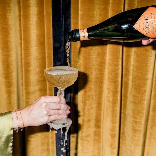 Close up of hand holding champagne glass with champagne being poured in and overflowing.