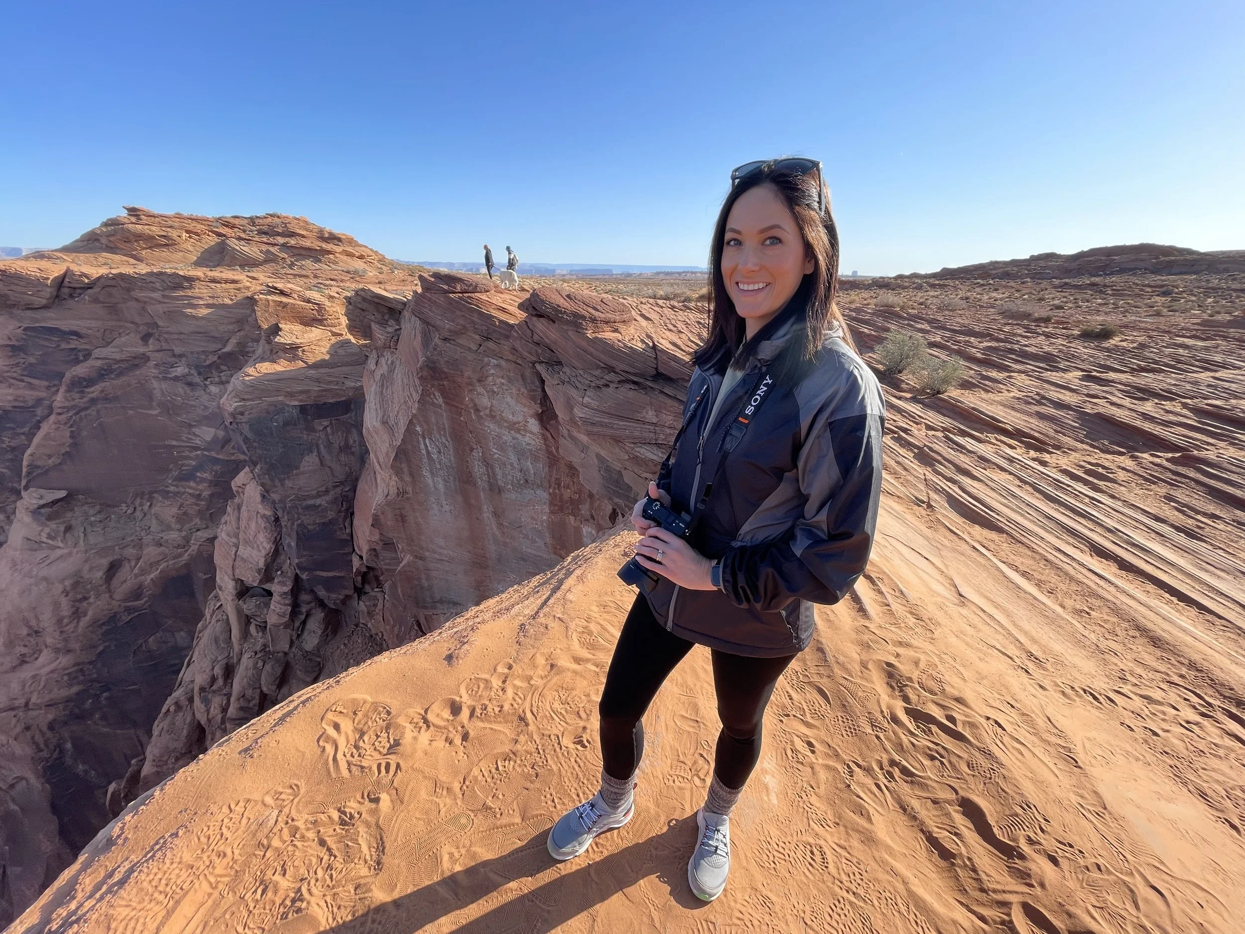 Valerie, CFO of Brass Tacks Coffee Co., exploring a desert canyon landscape with camera, reflecting adventurous brand lifestyle