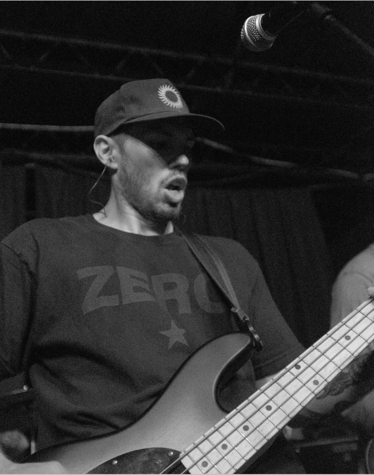 Taylor, Retail Director at Brass Tacks Coffee Co., performing live on stage with bass guitar, reflecting creative and music-driven culture