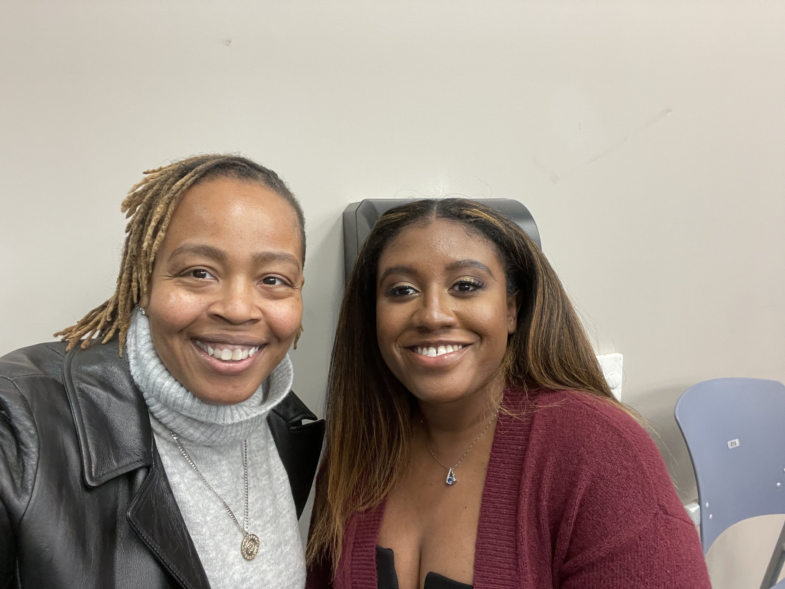 Two smiling women taking a selfie together in an indoor setting.