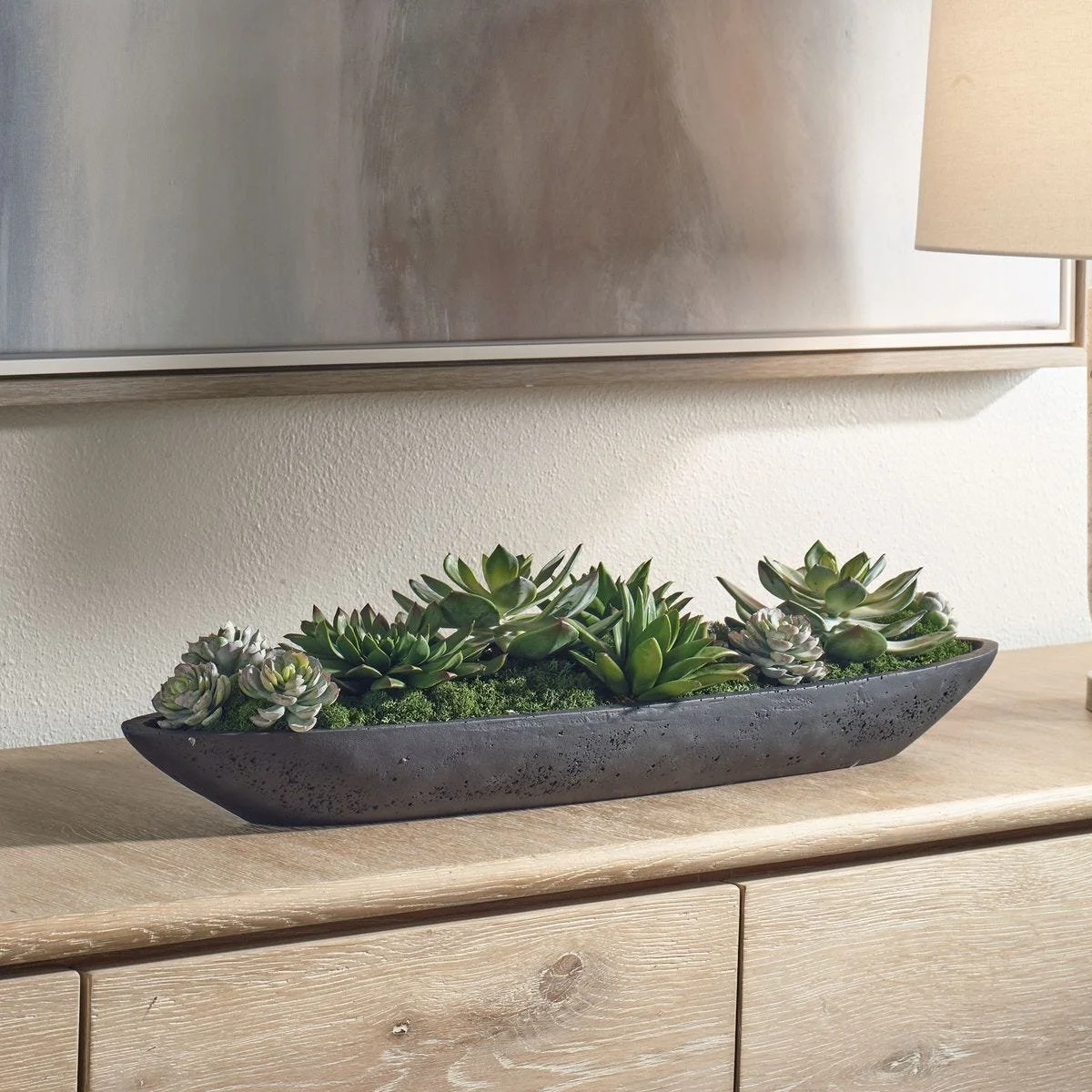 Long black man-made stone boat container holding lifelike succulent arrangement