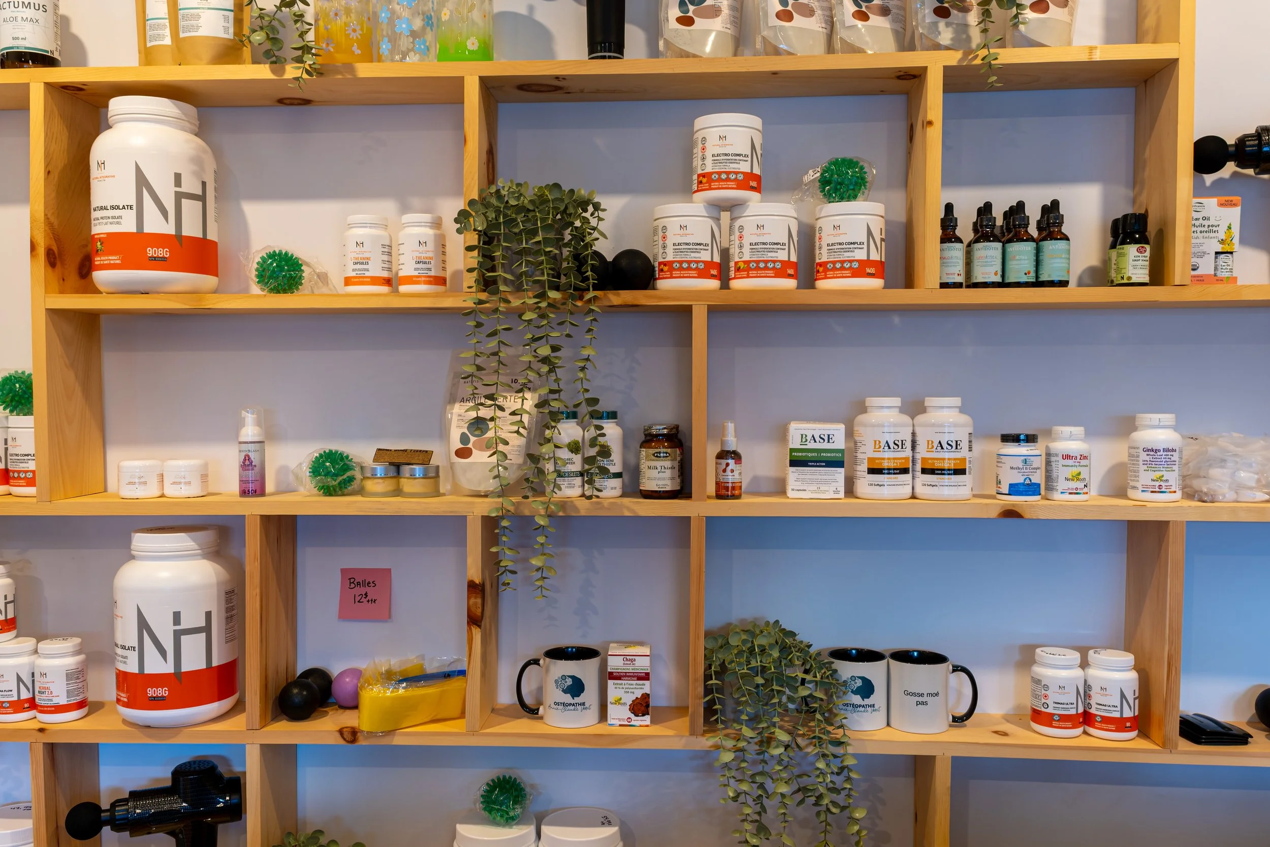 Étagères en bois remplies de compléments alimentaires, produits naturels, tasses, plantes décoratives et divers petits objets.