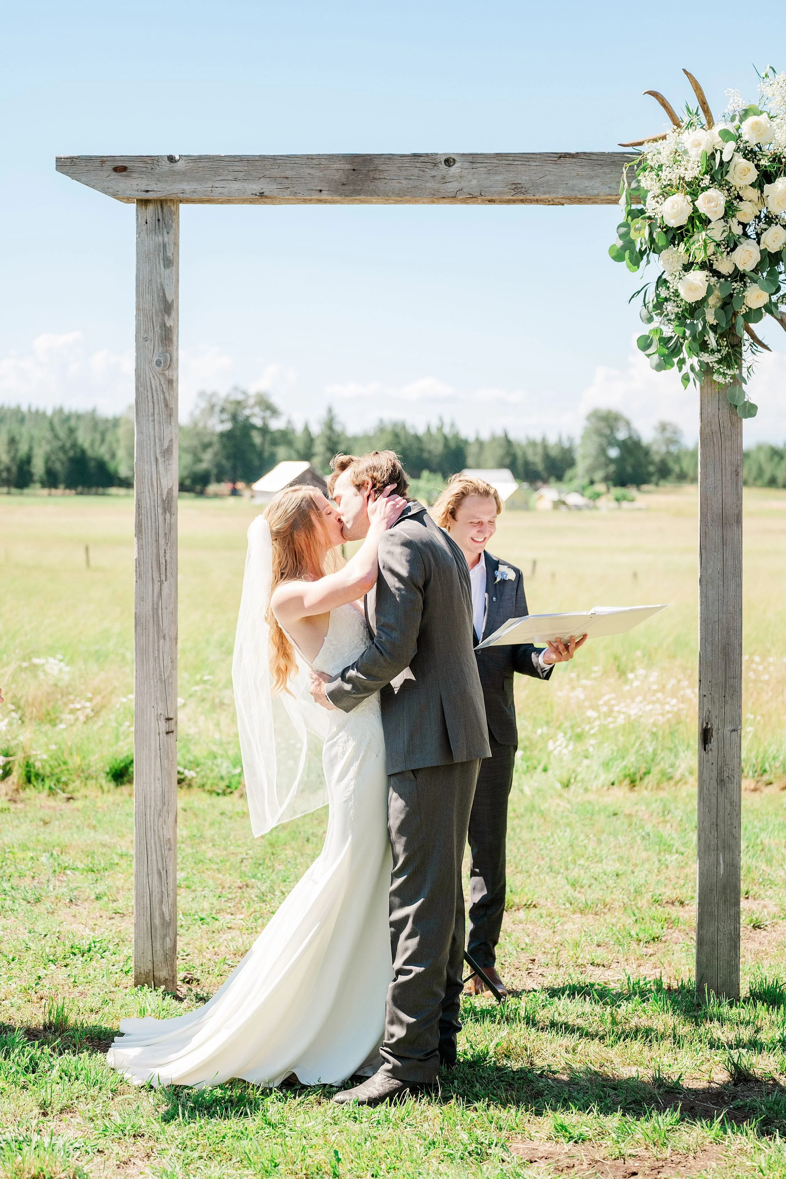 Bride and groom sharing their first kiss during their outdoor ranch ceremony.