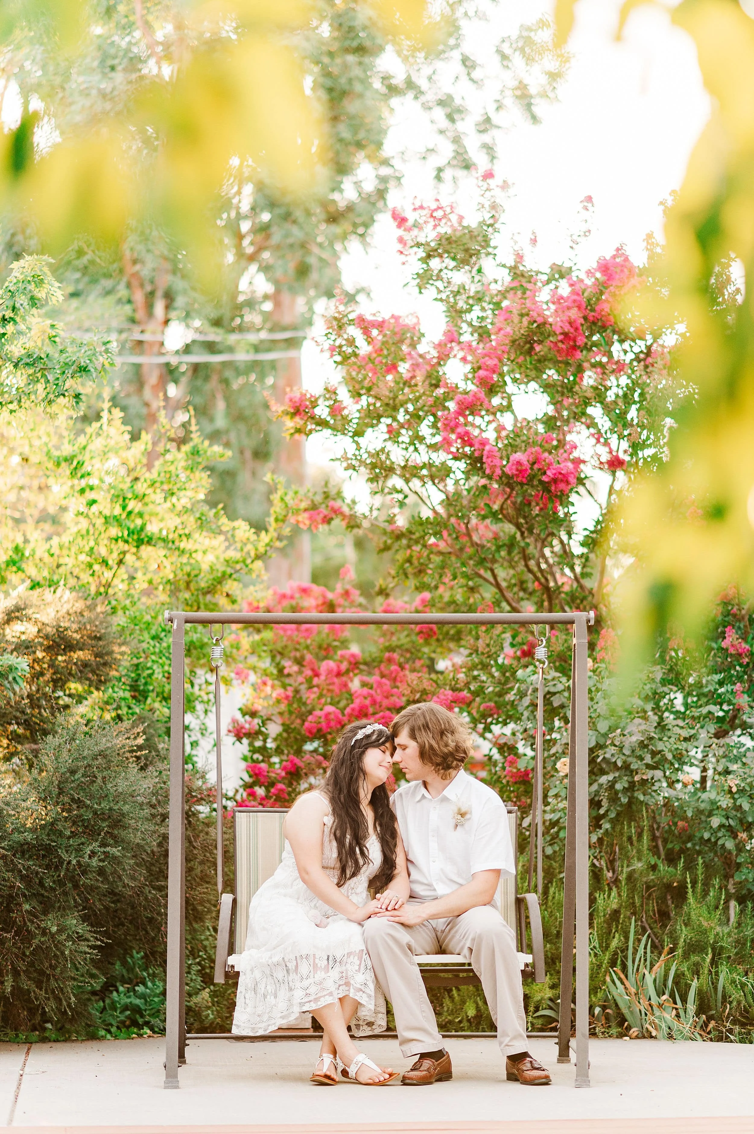 couple leaning into each other while sitting on porch swing at sunset