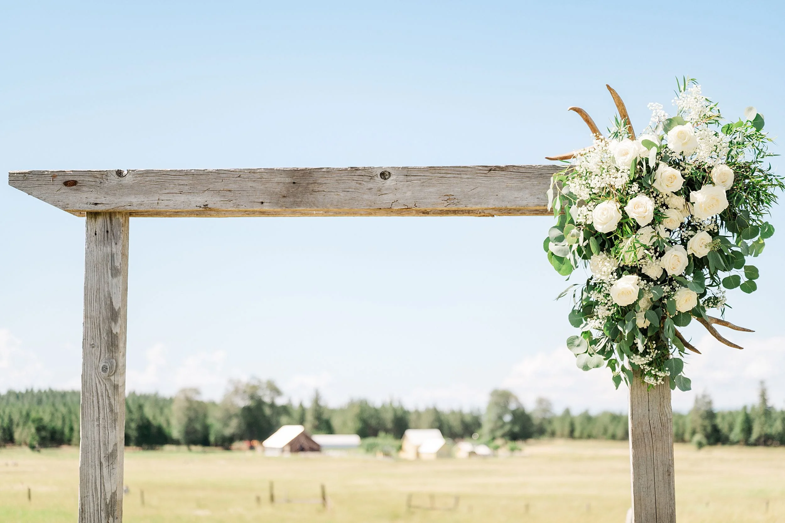 Floral ceremony arch with white and blue flowers at a private ranch wedding.