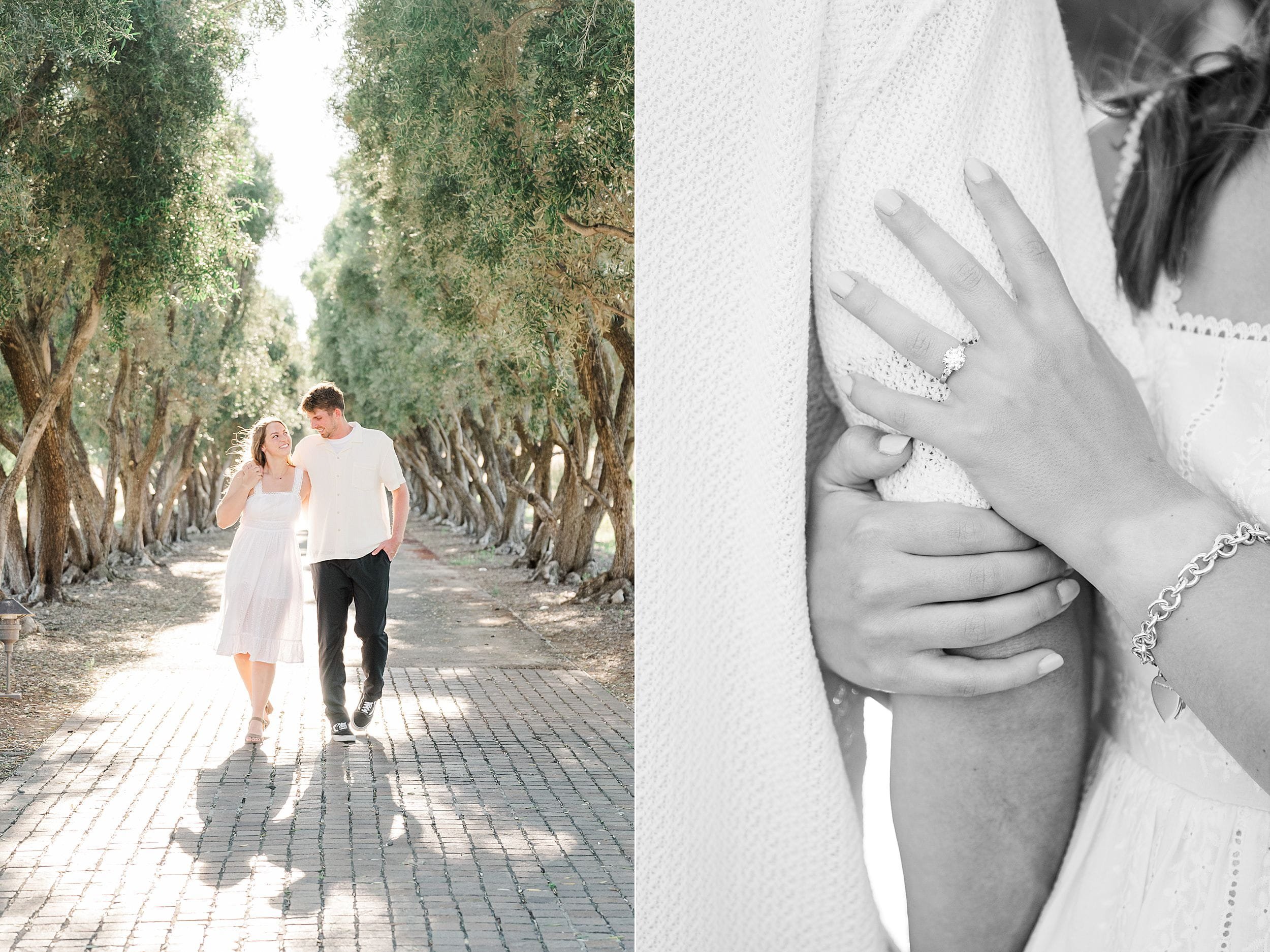 Couple walking under a canopy of trees on a sunlit path; she holds his arm, displaying a ring. The mood is romantic and serene.
