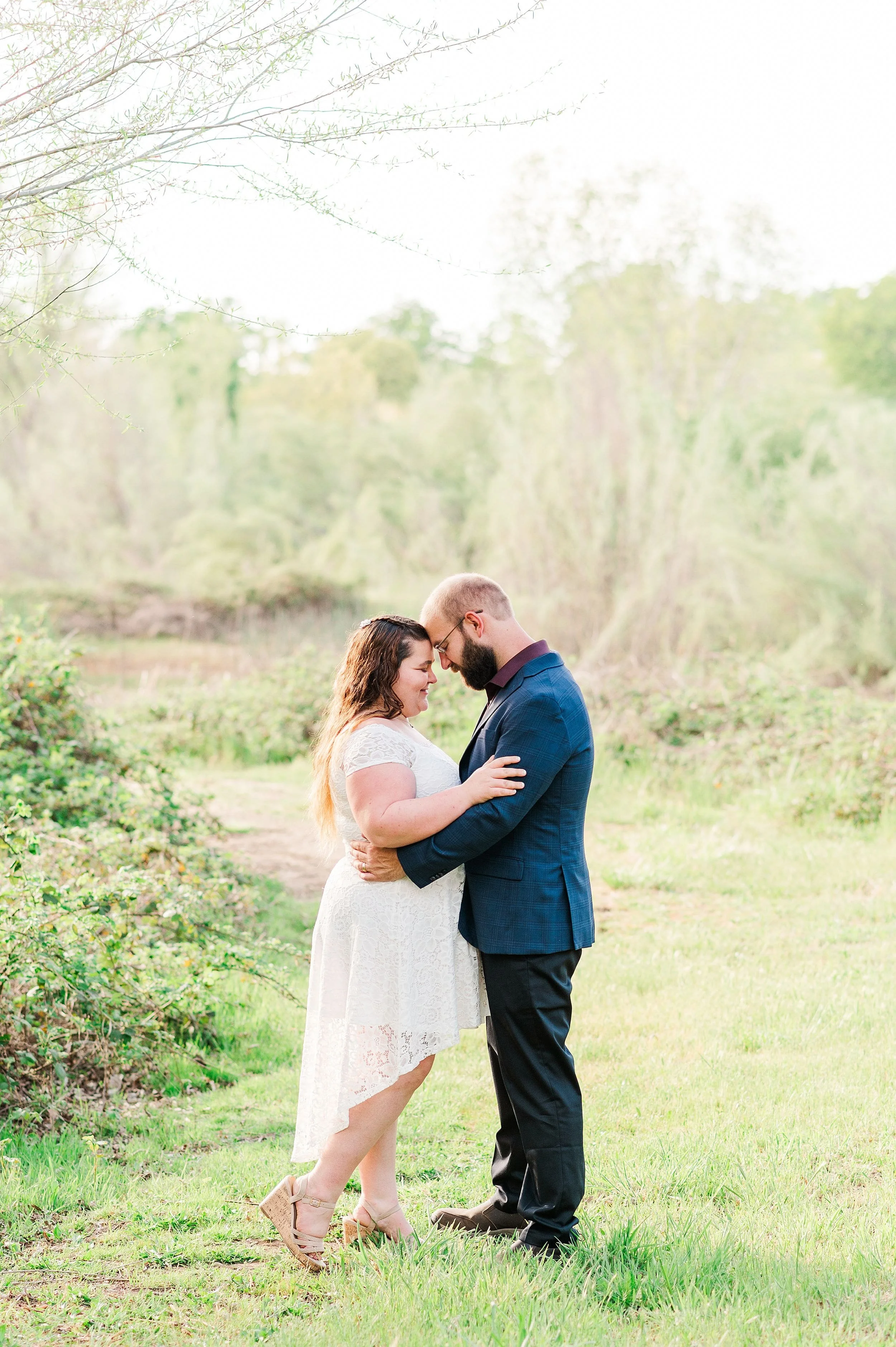 couple facing each other and touching forehead to forehead during spring engagement session
