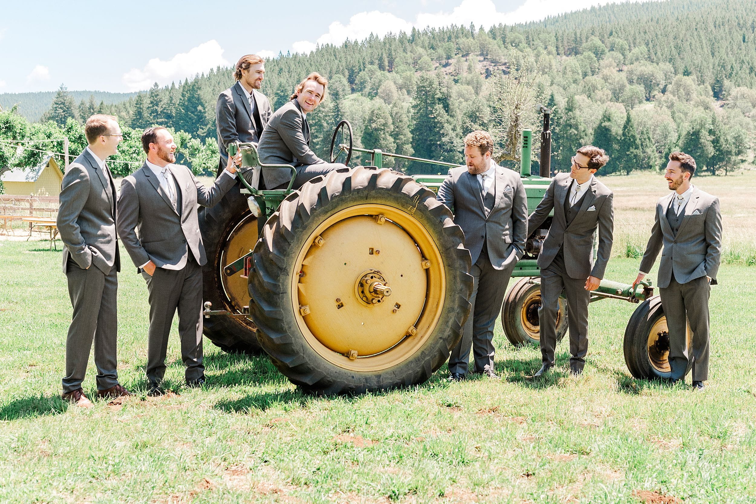 Groomsmen portraits on john deere tractor with mountain views at a private ranch wedding.