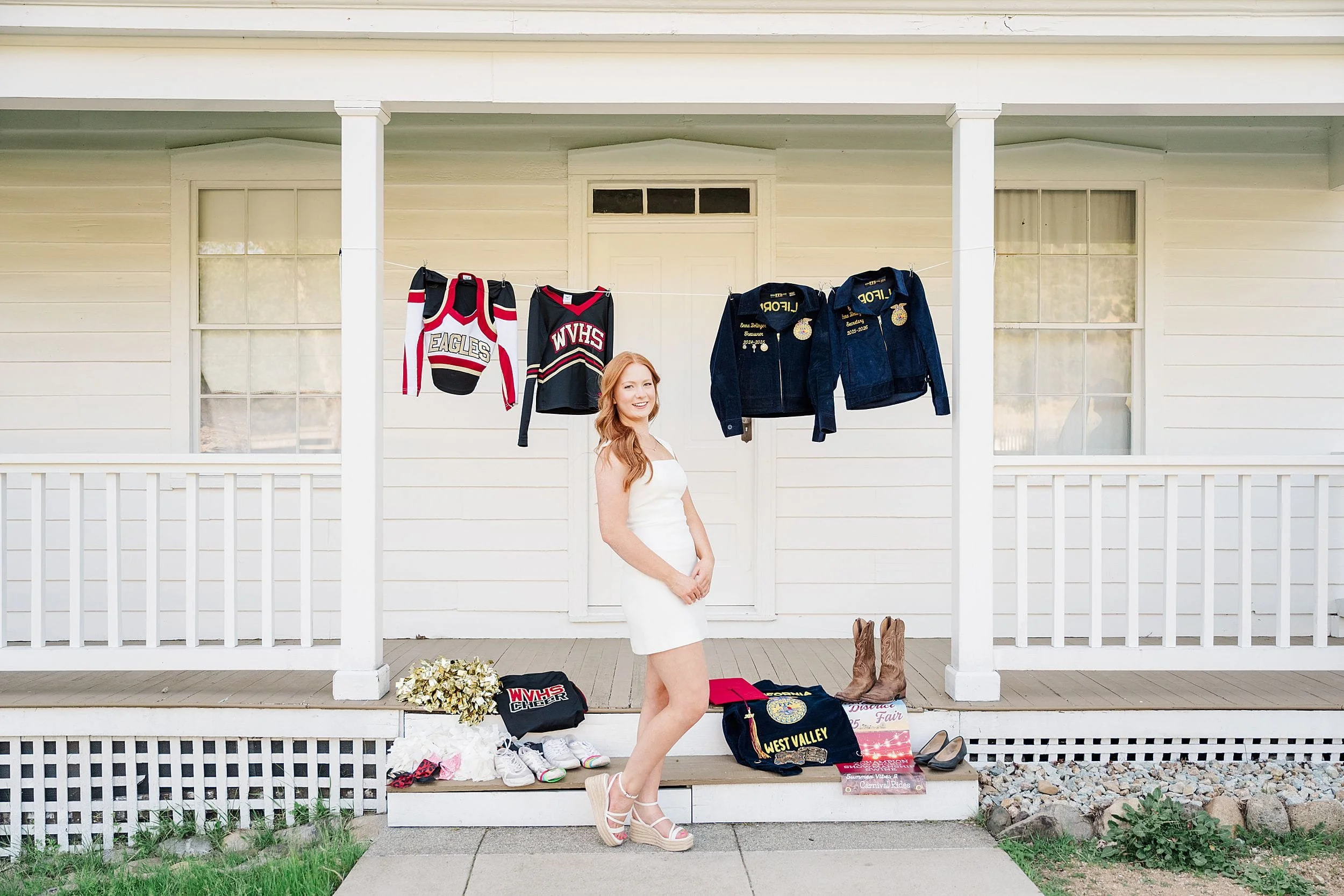 A young woman in a white dress stands smiling on a porch. Behind her, sports jerseys and jackets are displayed. Boots and other items are arranged below, indicating achievements and memories.
