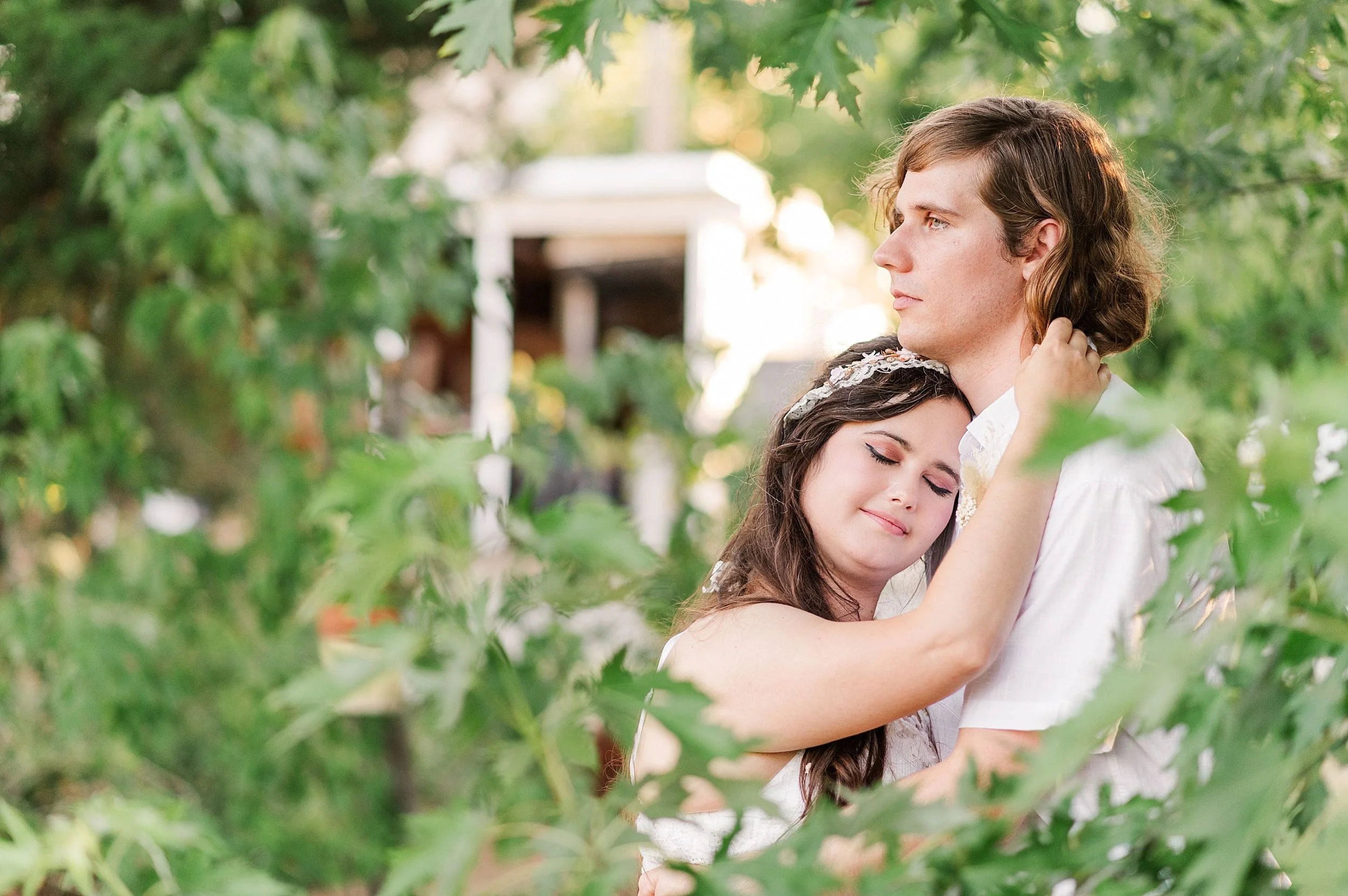 girl hugging and leaning head on fiance's chest surrounded by leaves