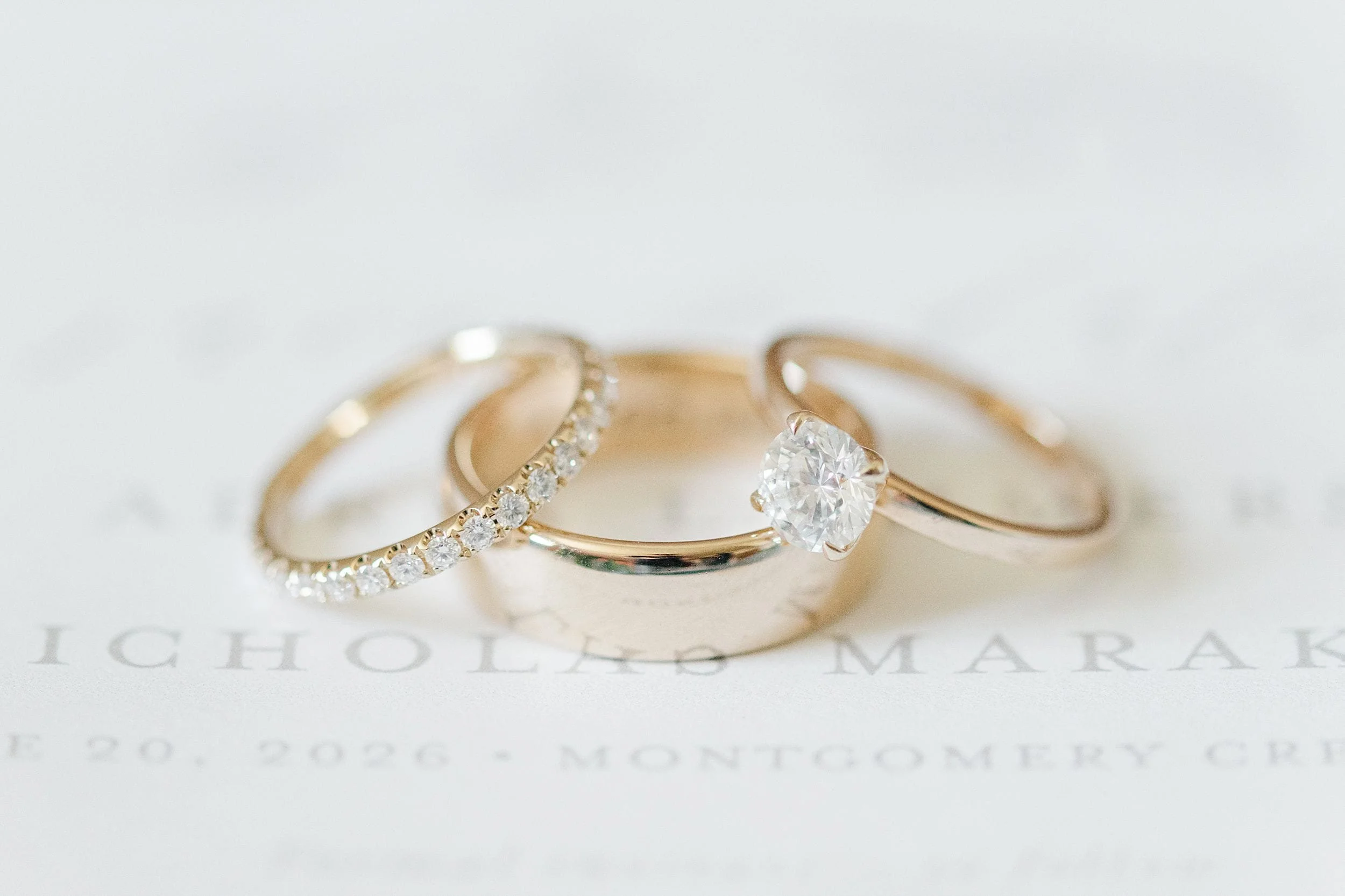 Diamond engagement ring and wedding bands photographed on the wedding invitation.