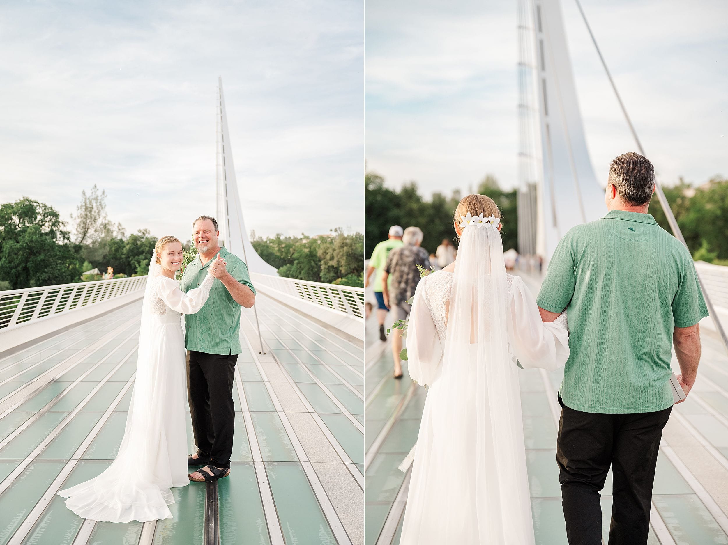 A bride in a white gown and veil smiles while dancing with a man in a green shirt on a modern bridge. The sky is clear, and trees frame the scene.
