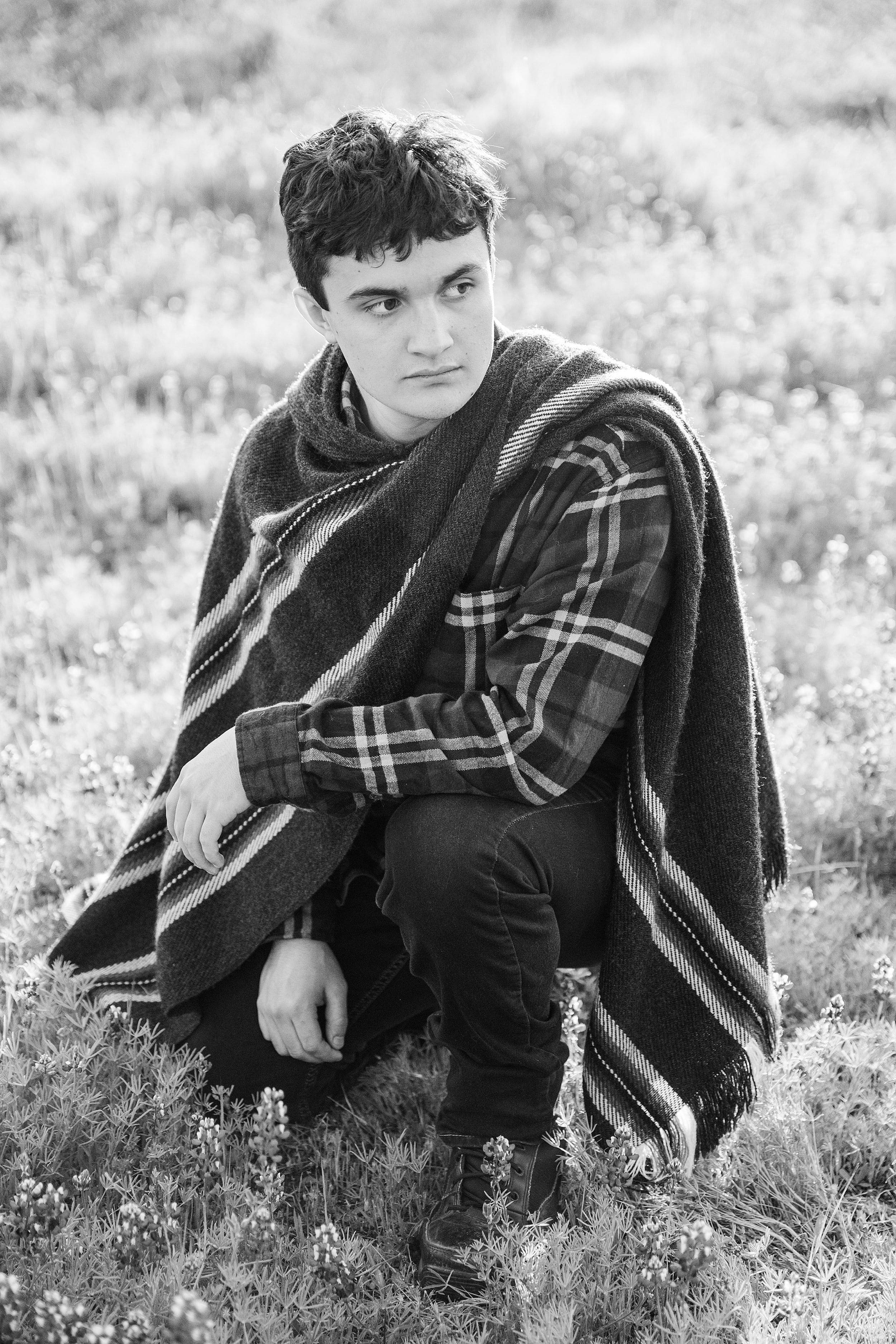 black and white photo of high school senior wearing plaid shirt and poncho