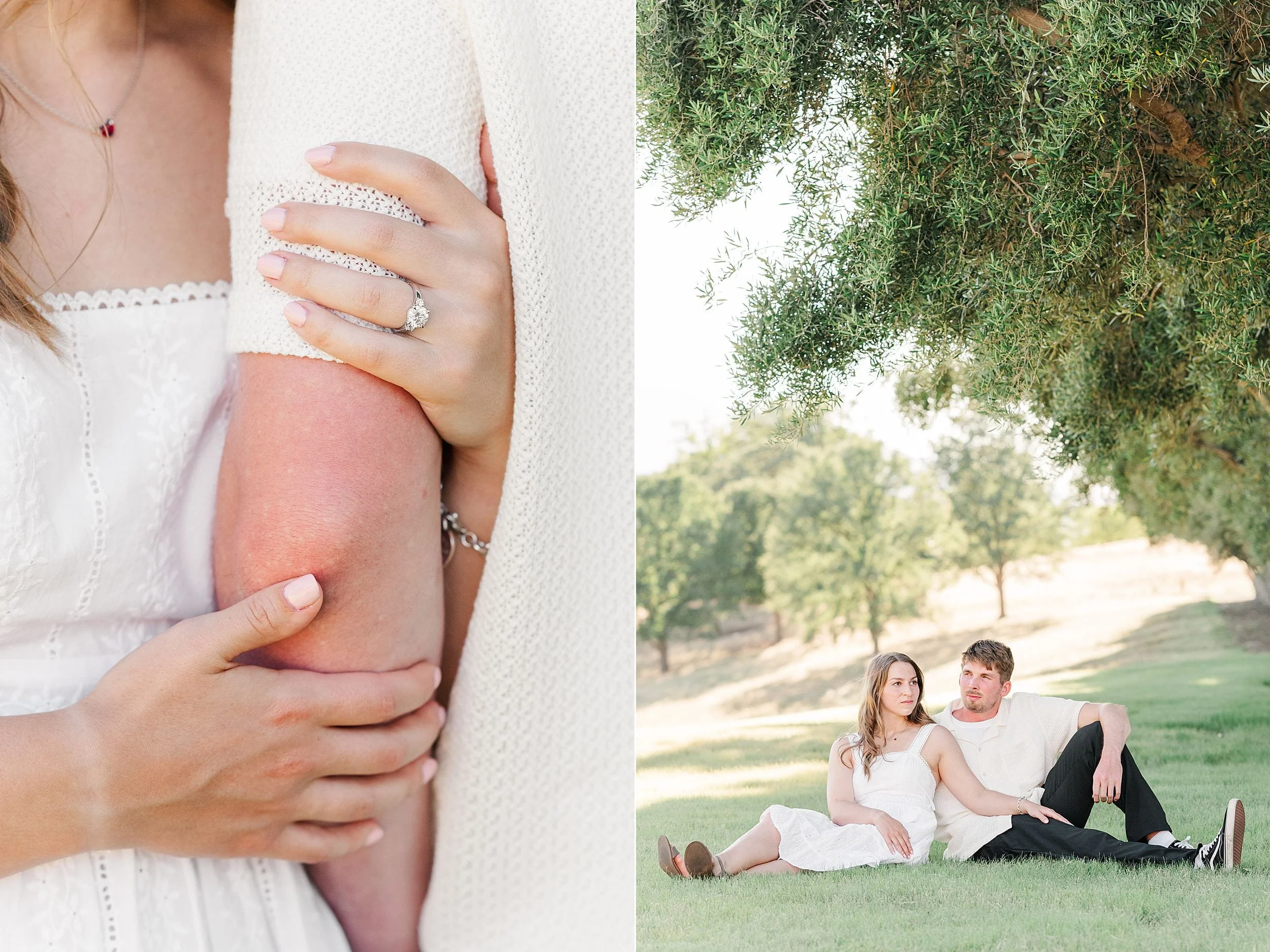 A woman in white shows her engagement ring while holding a man's arm. Beside them, they sit on green grass under a tree, exuding a romantic, serene vibe.