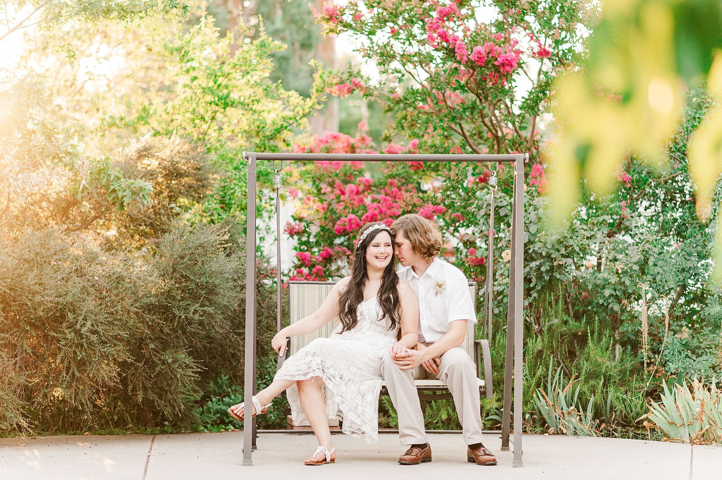 engaged couple sitting on porch swing in the garden at sunset