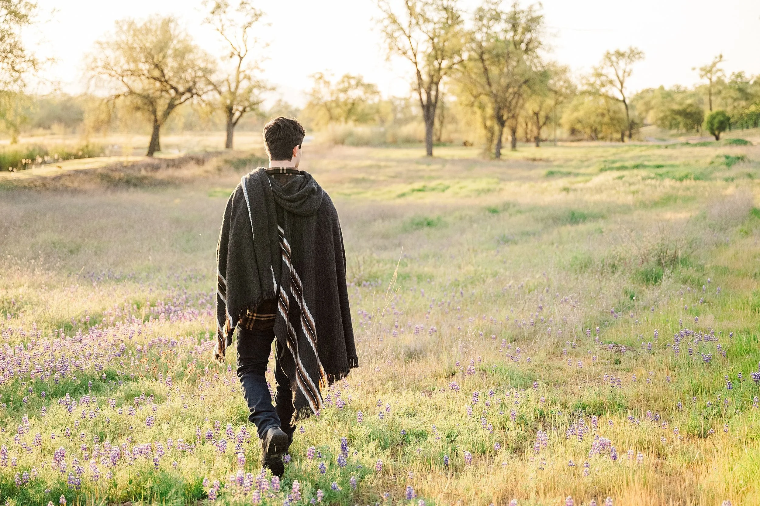 teenage boy walking through field of wildflowers