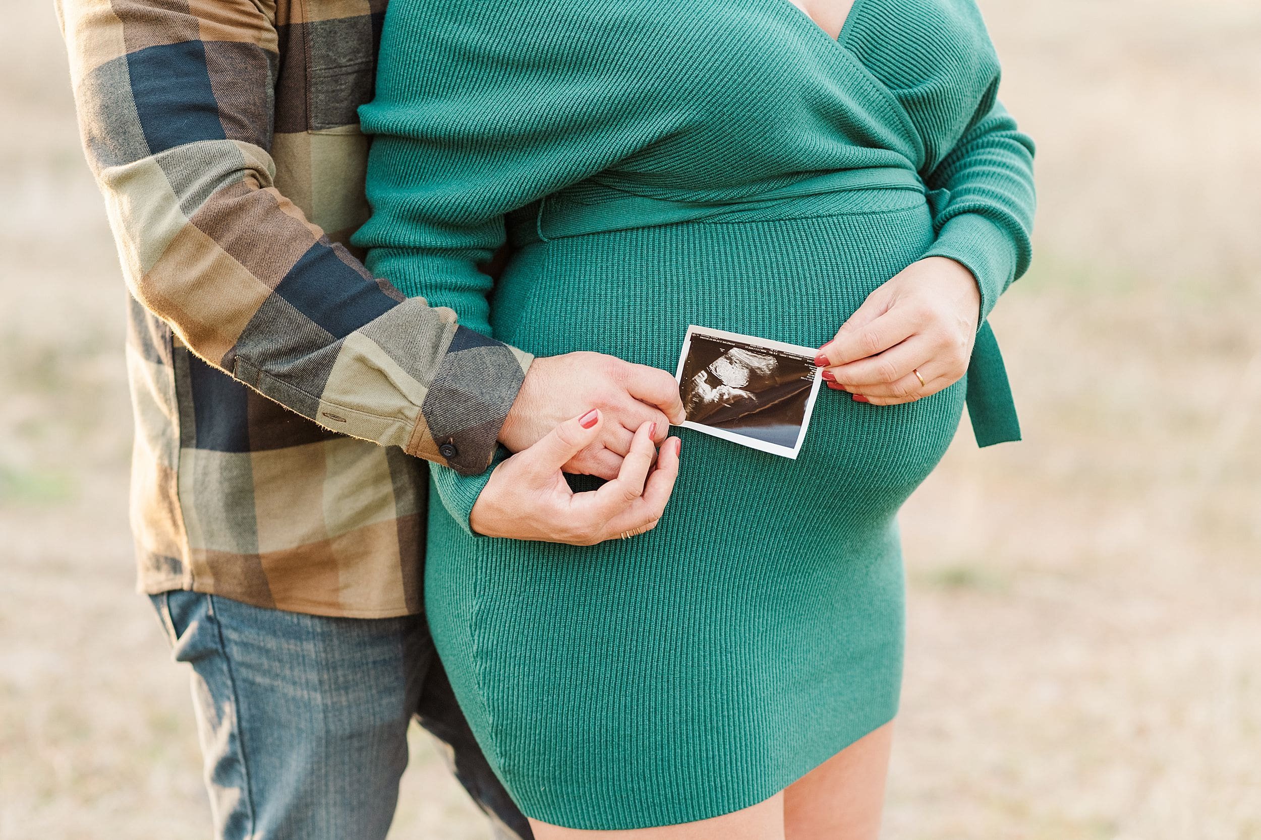 sonogram photo being held by parents hands on pregnant belly