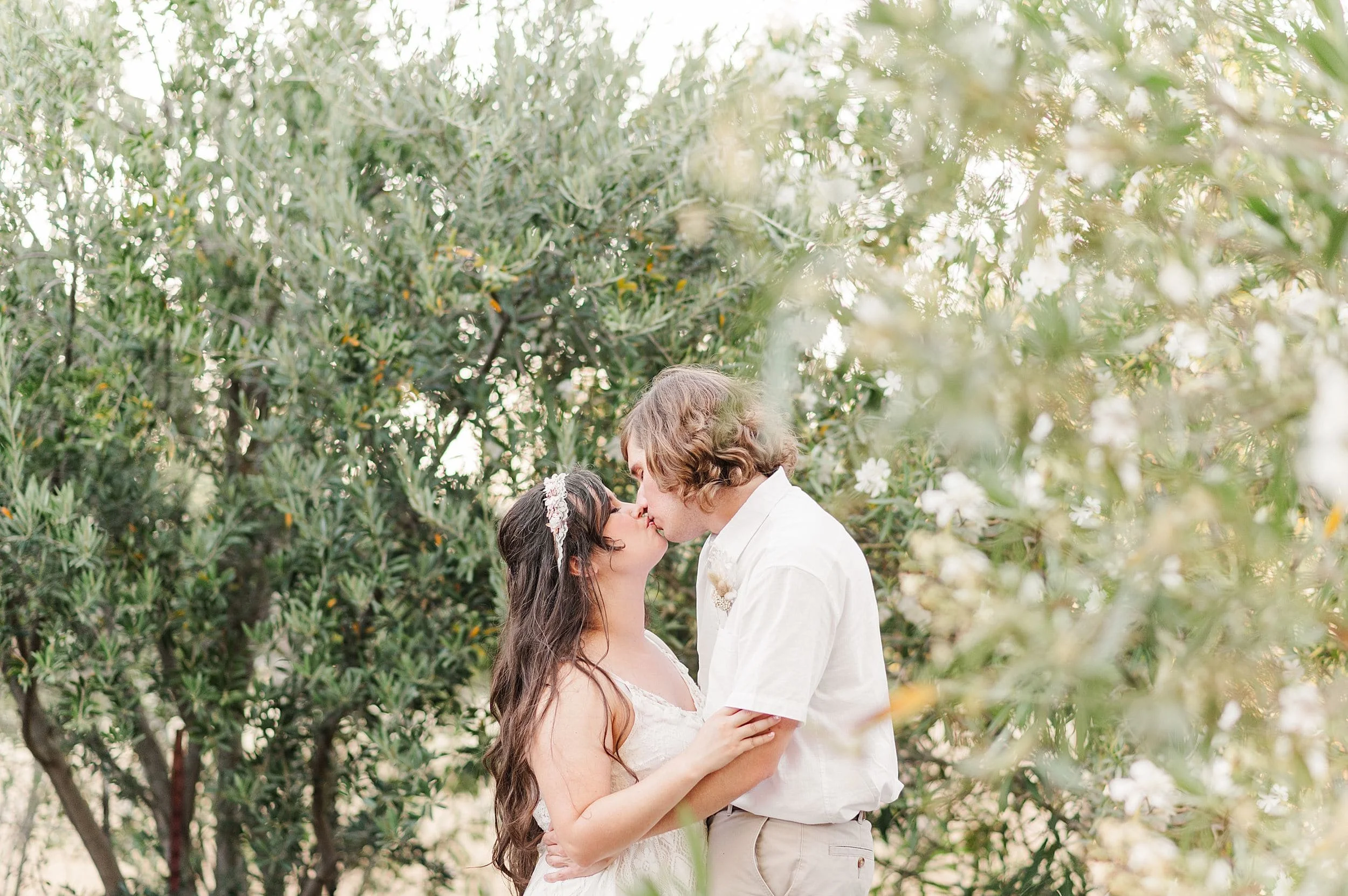couple sharing kiss surrounded by greenery