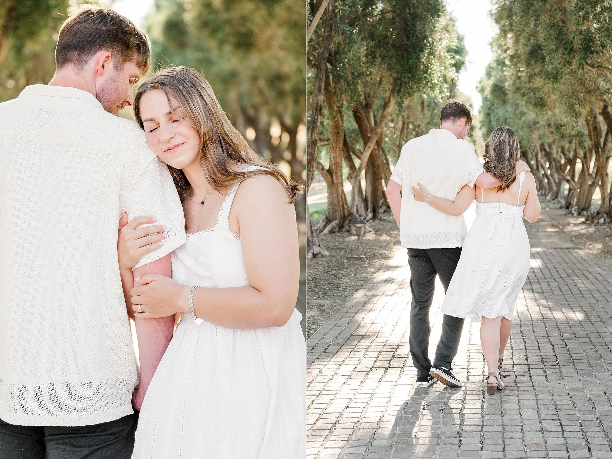 A couple in white clothes walk arm-in-arm on a sunlit tree-lined path. She leans on him with eyes closed, conveying warmth and serenity.