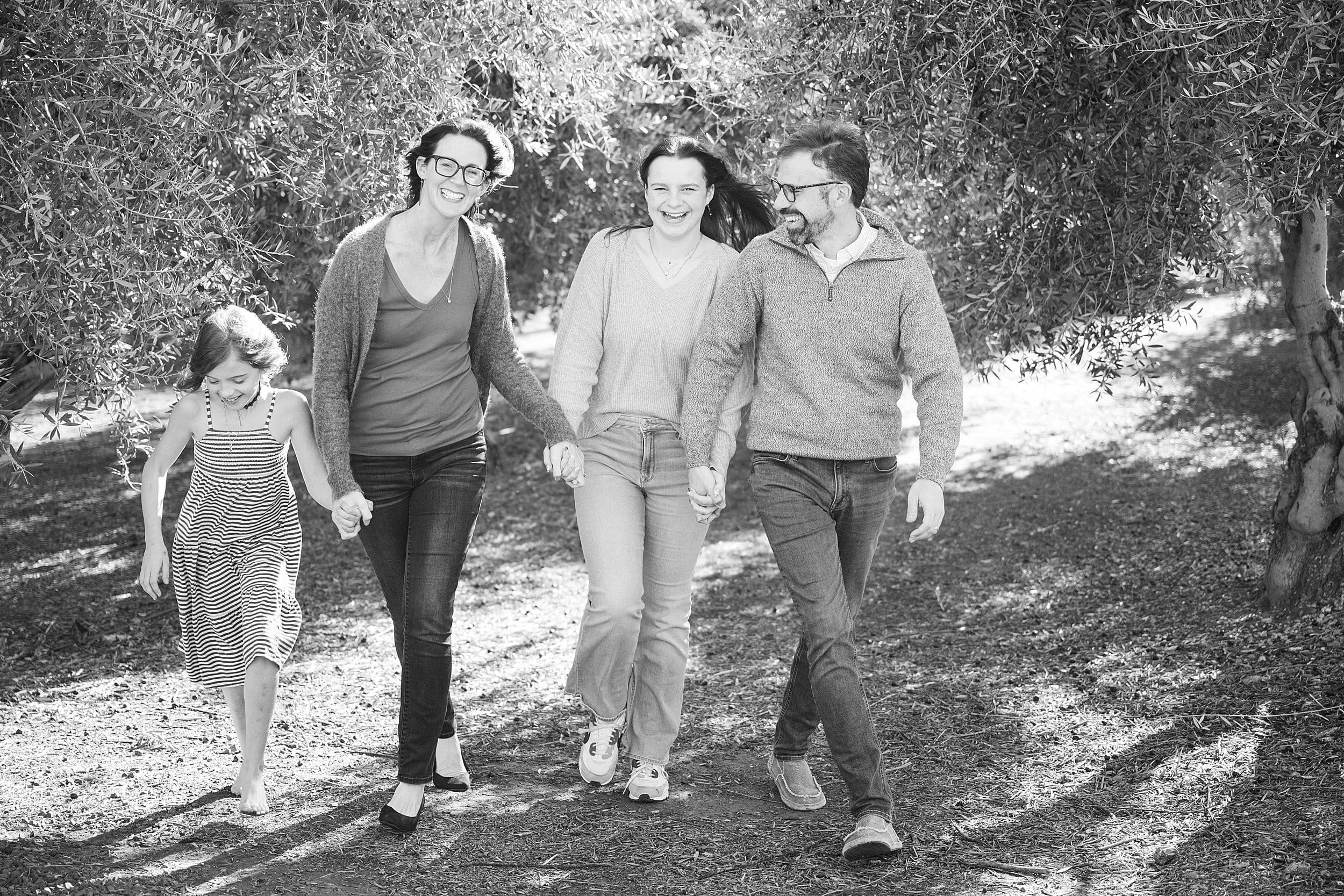 family walking and laughing through olive tree orchard