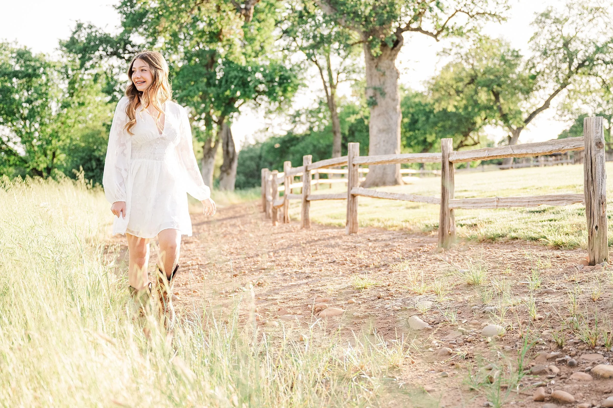 young girl walking down path by wood fence