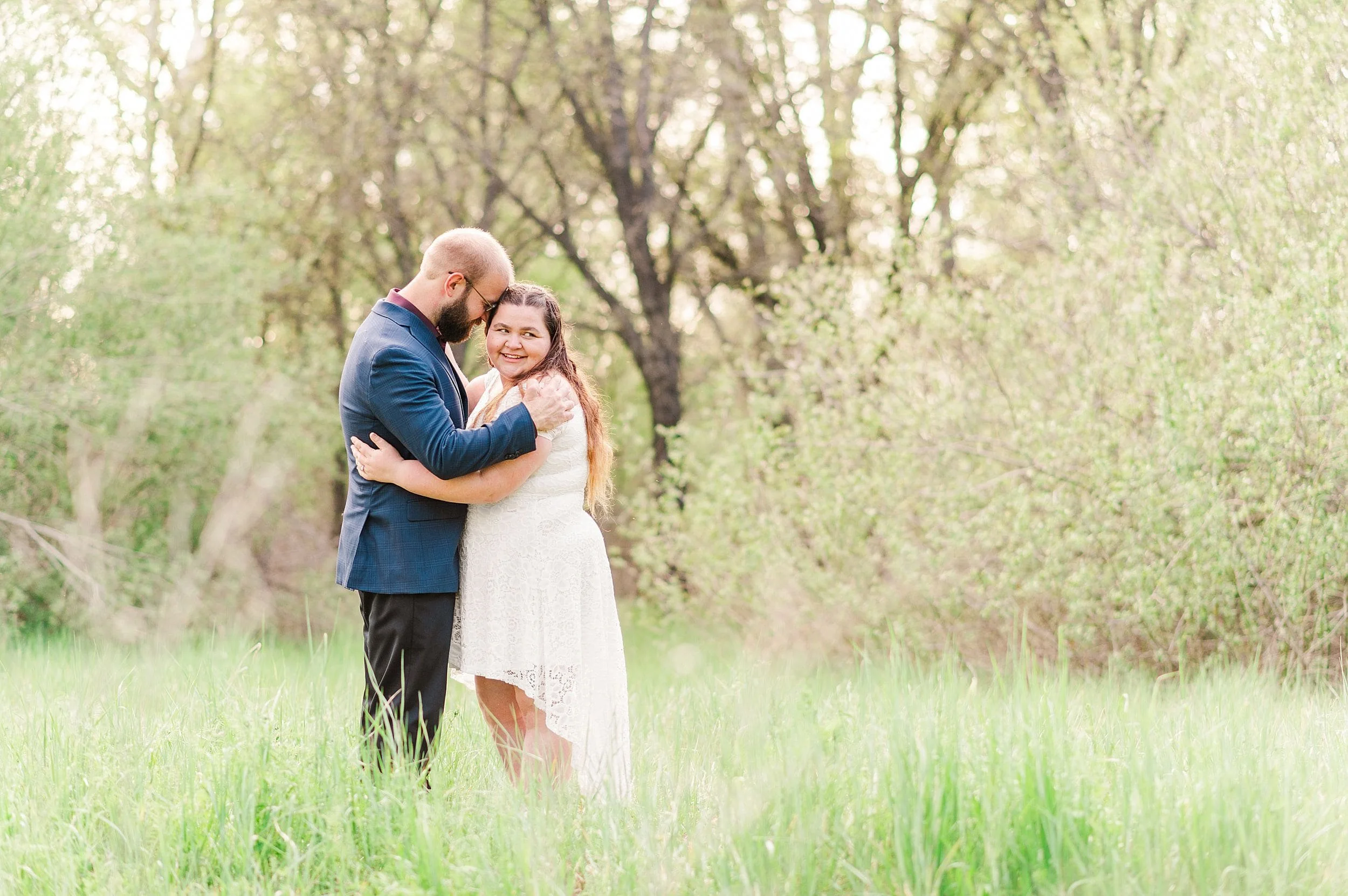 engaged couple hugging while woman is smiling over her shoulder