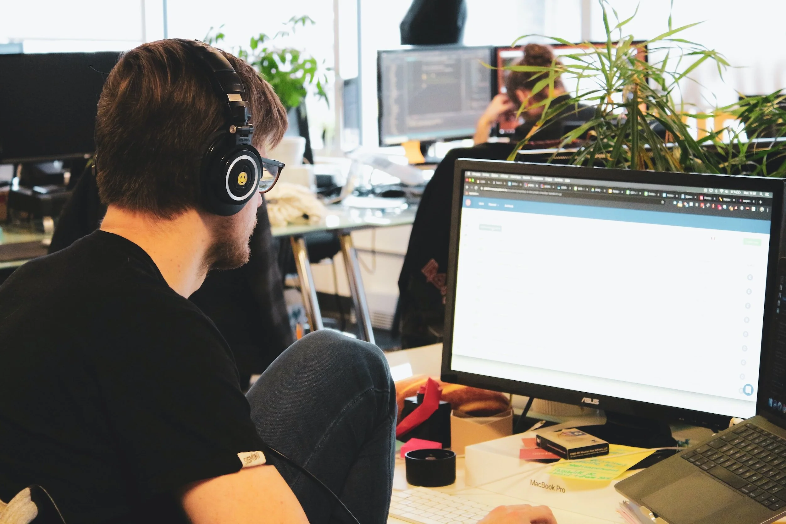 person working at desk computer station wearing headphones
