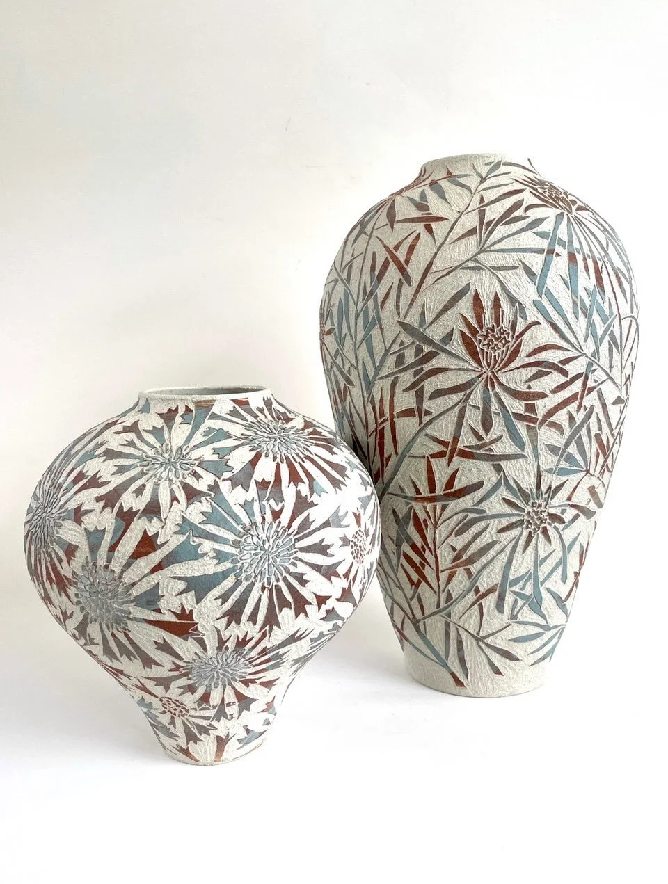 More fired pots from my Wollemi series: Broad-leaved Drumsticks (Isopogon anemonifolius) and Mountain Devil (Lambertia formosa).

These are coil-built, painted with slip reclaimed from sgrafitto shavings, and carved to create the botanical design. I 