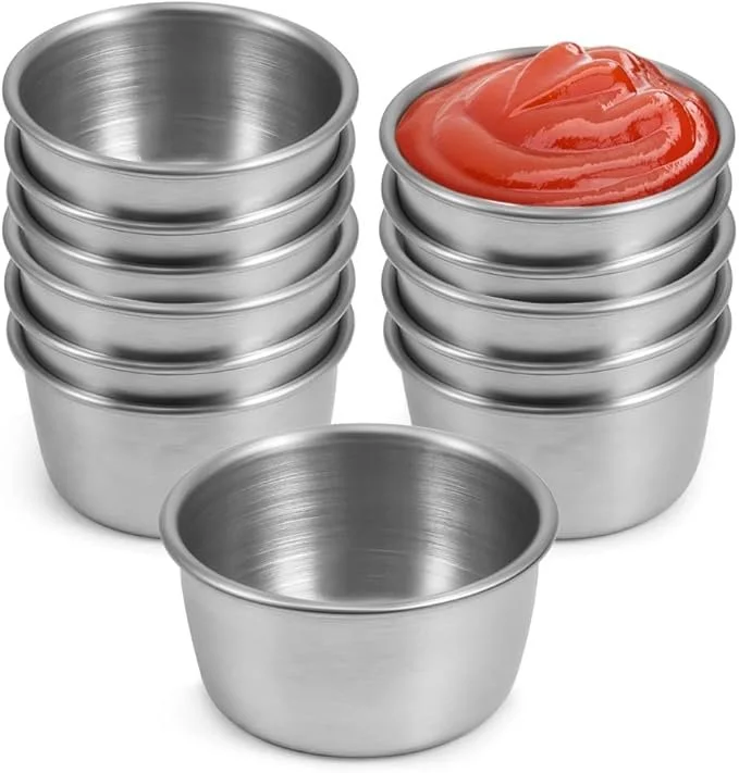 Stacked stainless steel cups with one filled with ketchup.