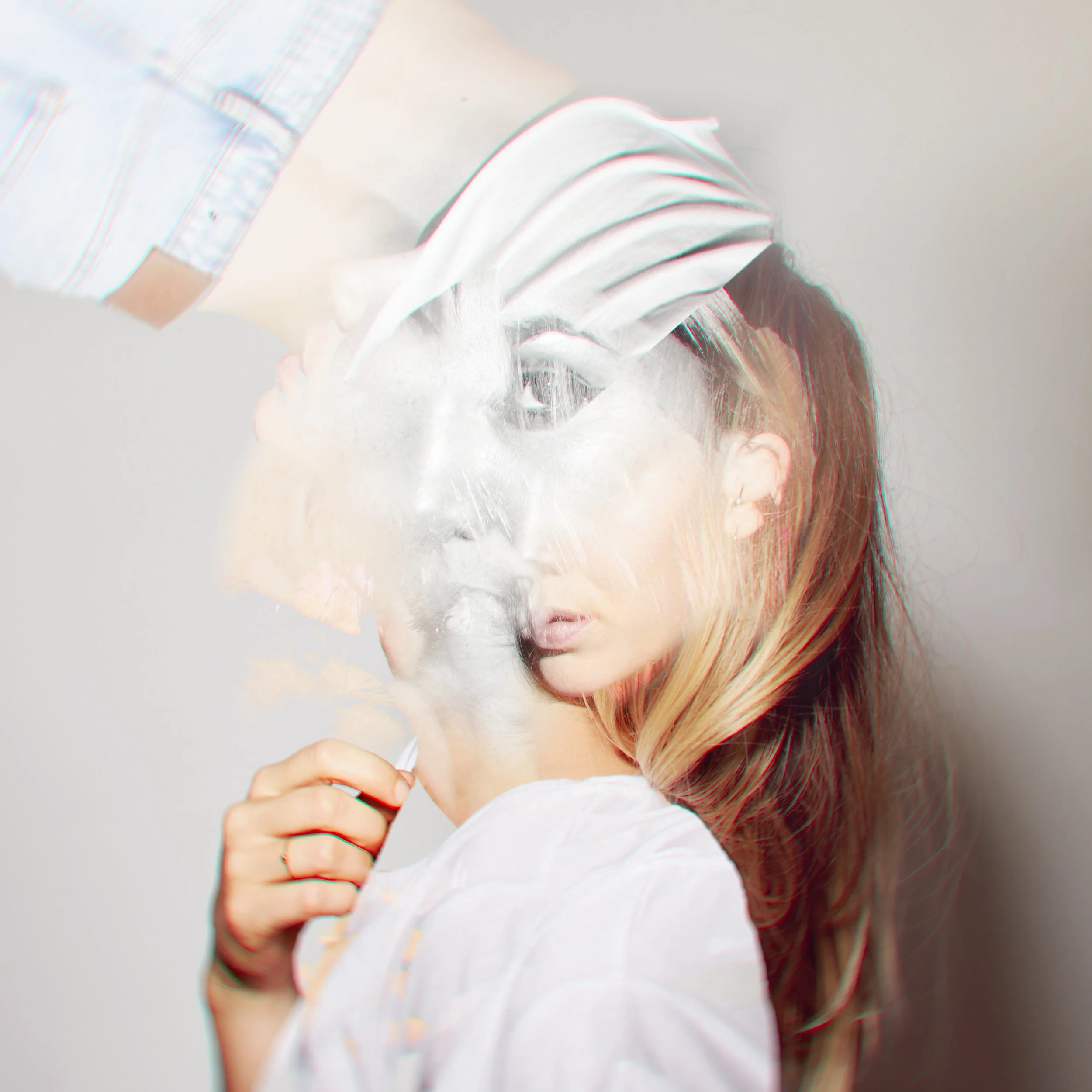 Eine Person, die ein weißes T-Shirt trägt, eine Collage. Die Person hat blone lange Haare. Die Aufnahme ist unscharf oder verzerrt, was den Eindruck eines trüben oder glitchhaften Effekts vermittelt.