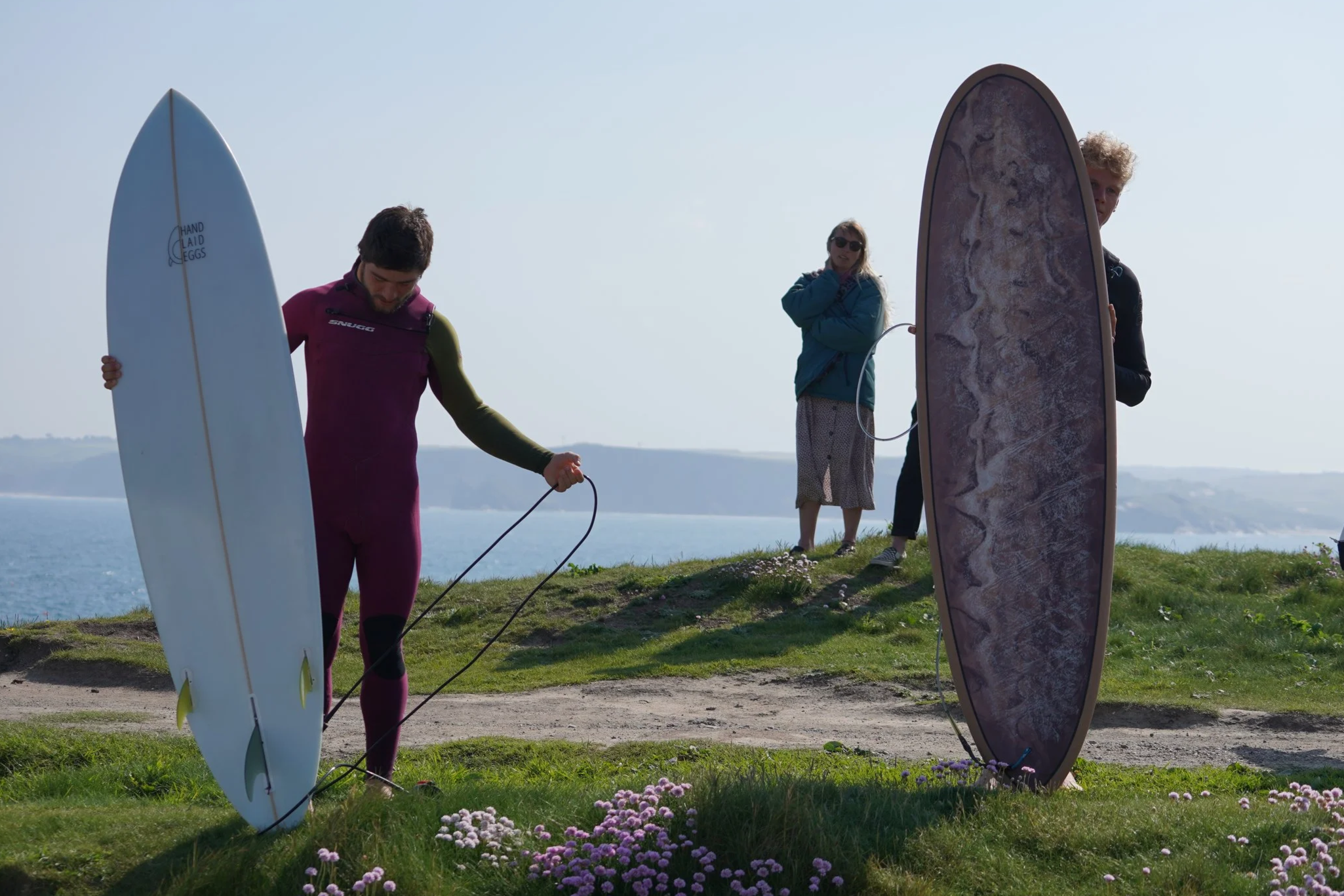 two surfers hold surfboards, one is a mid length the other is a mini-mal