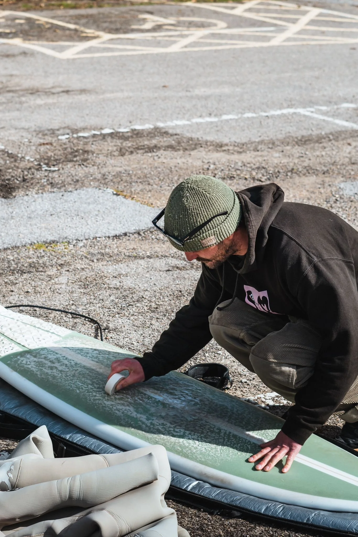 surfer waxes their surfboard after fixing it