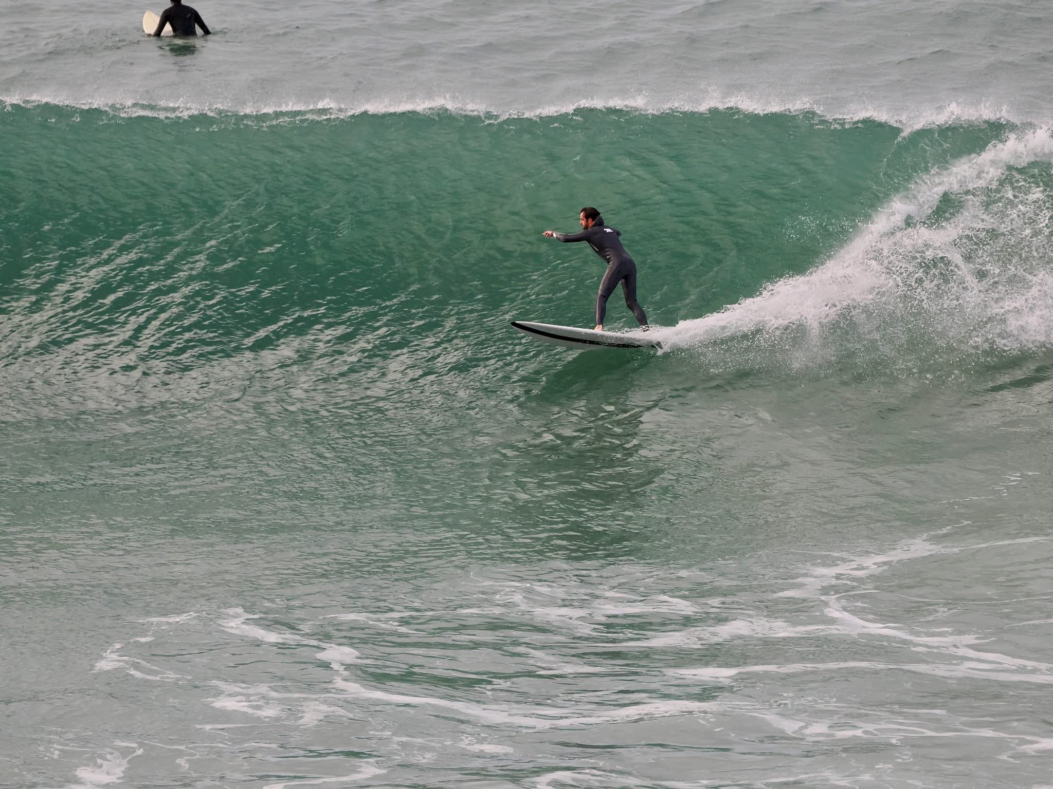 surfer riding a twin fin surfboard in uk waves