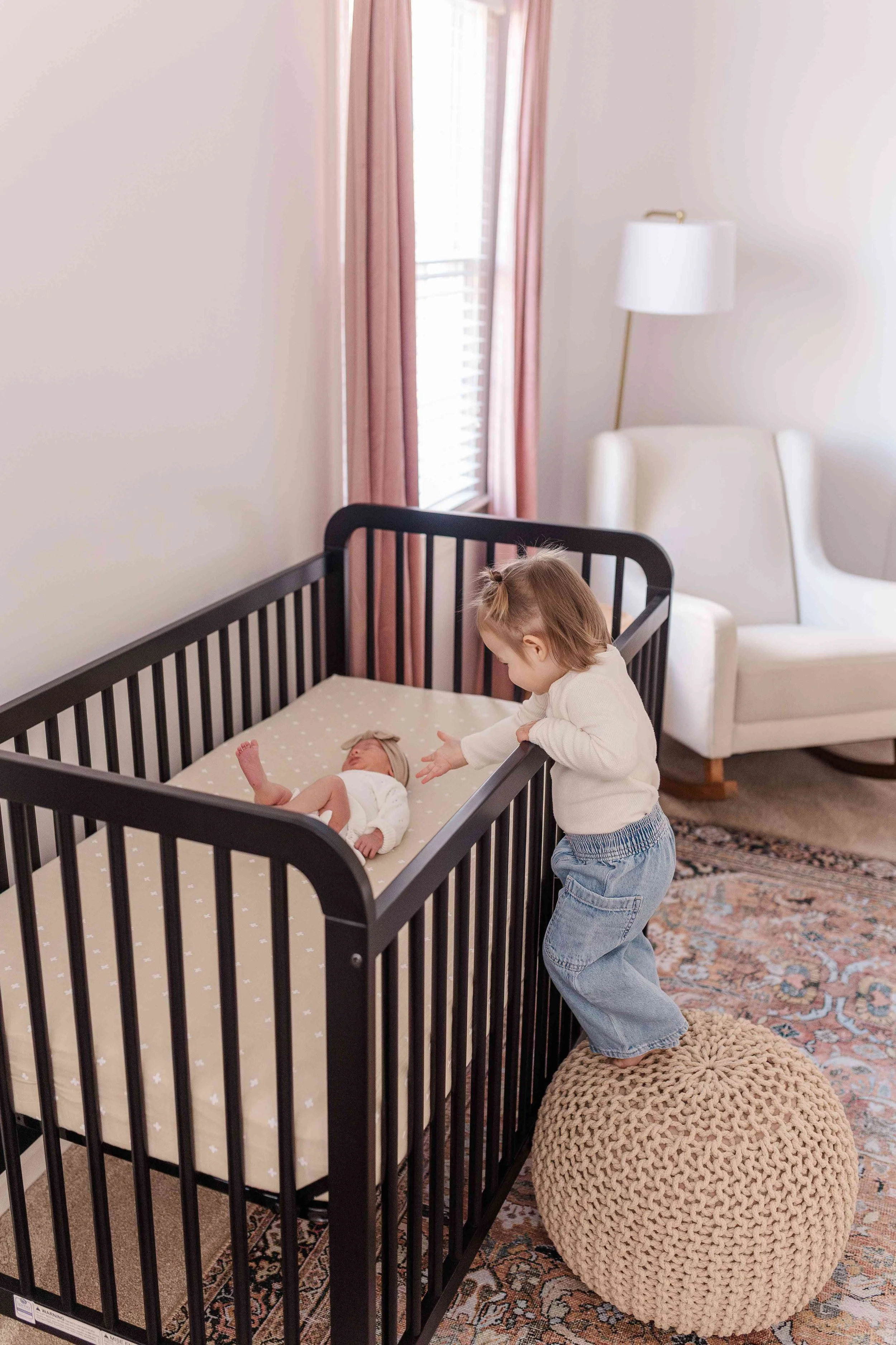 Toddler big sister looking into black crib at newborn baby, lifestyle newborn session Easley SC