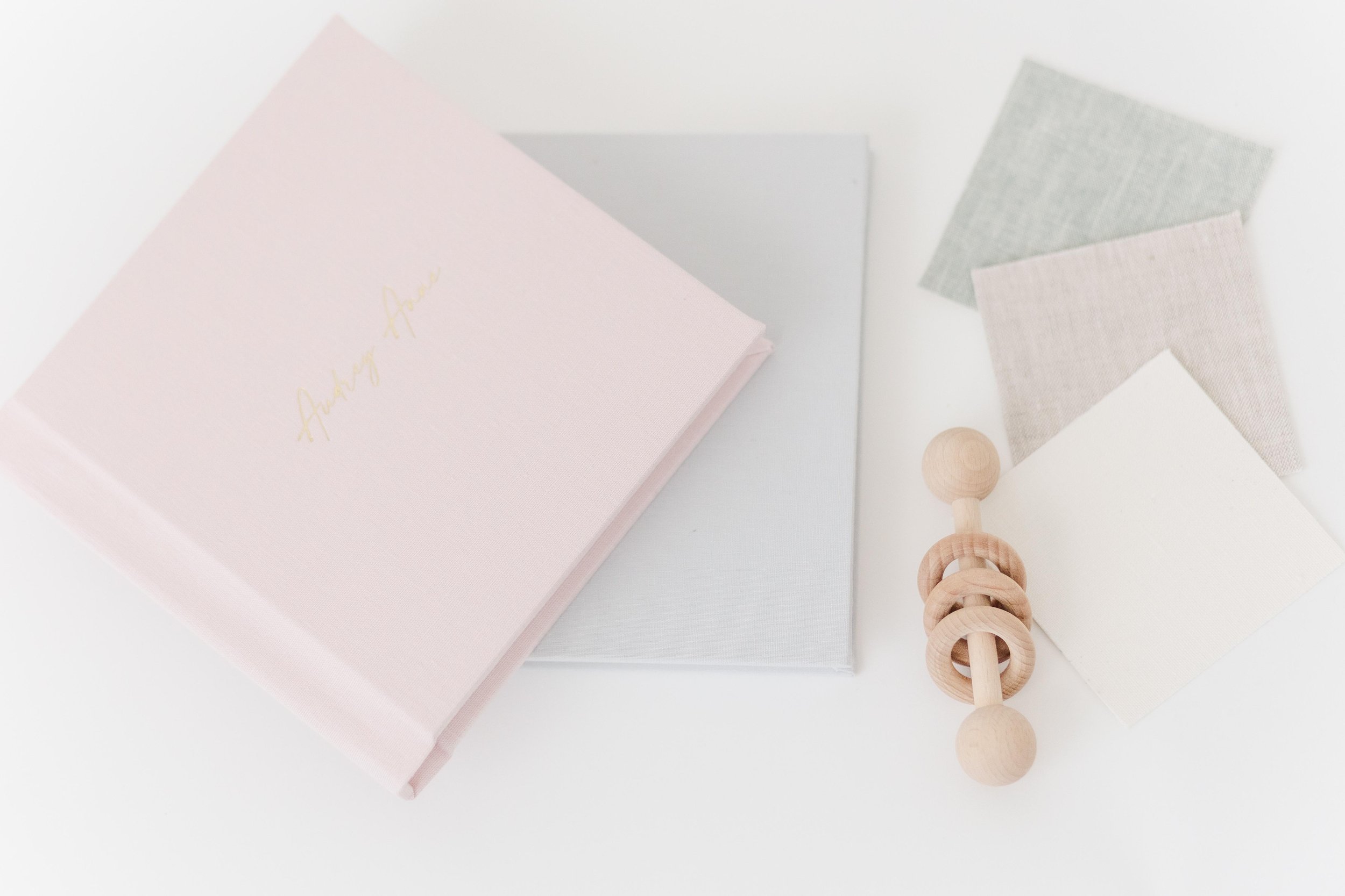 A collection of pastel-colored papers, a wooden rattle, and fabric swatches on a white surface.