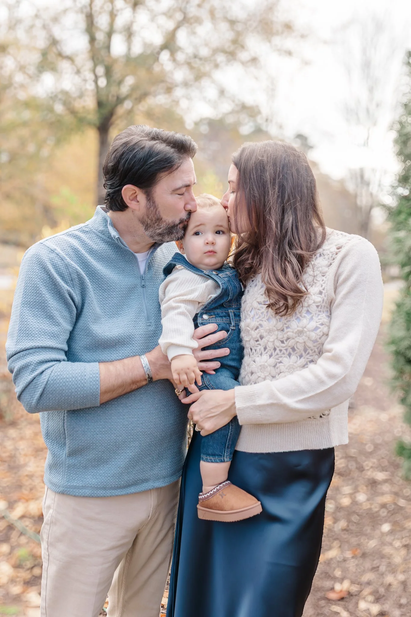 parents kissing cheeks of baby at anderson family session at linley park