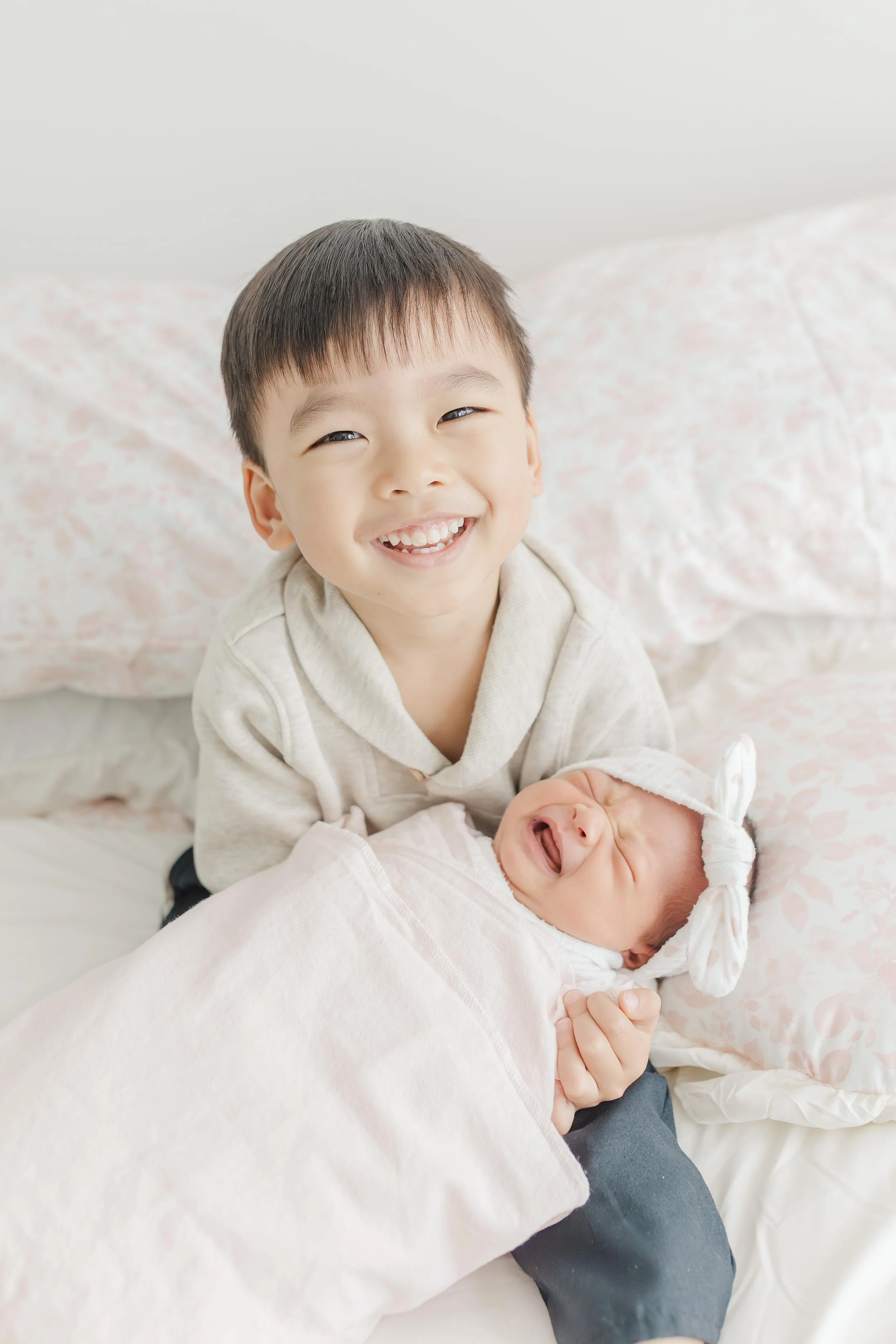 Big brother smiling proudly while holding his newborn baby sister — Greenville South Carolina newborn photography