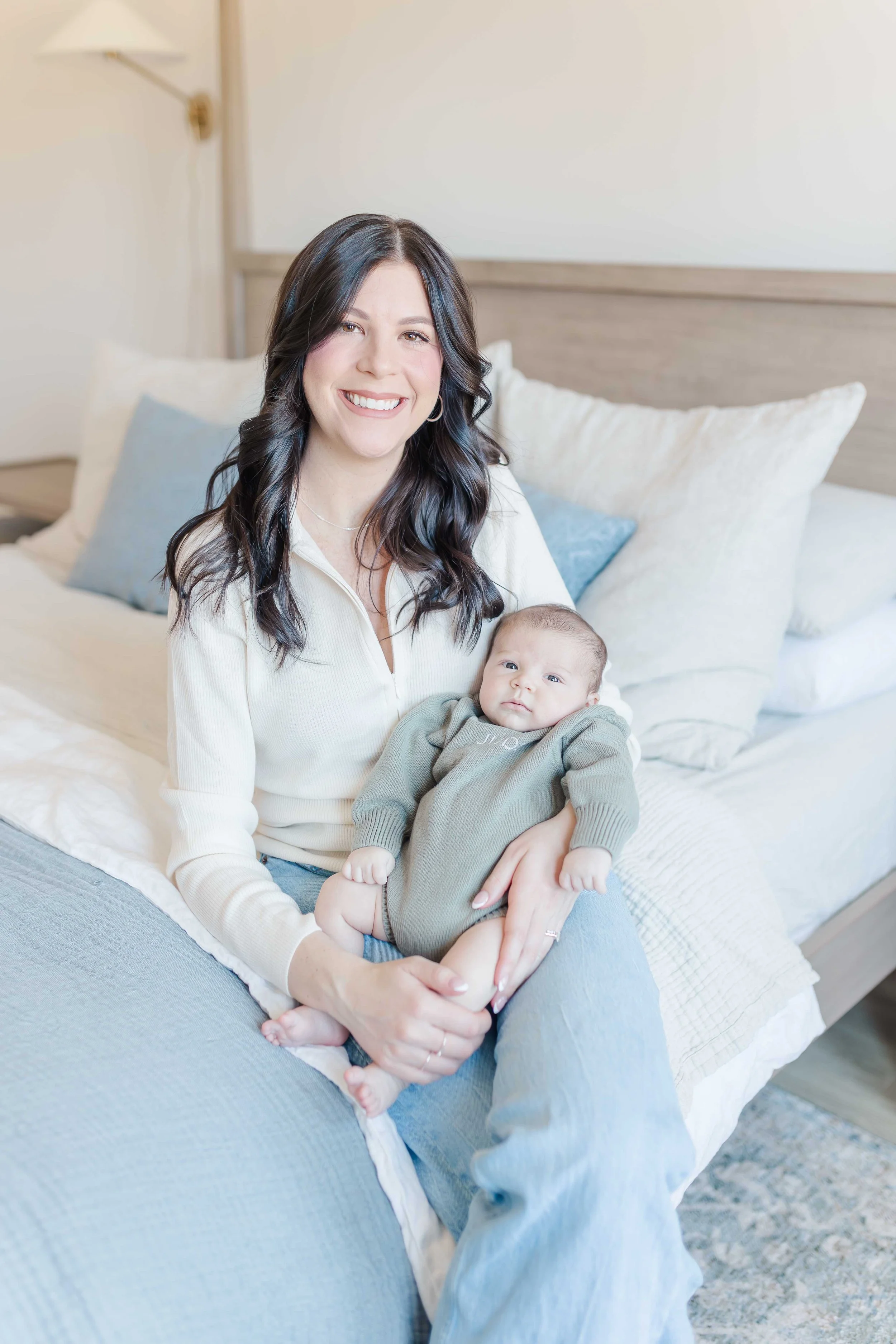 Mom holding newborn baby boy on upholstered canopy bed, lifestyle newborn photographer Piedmont SC