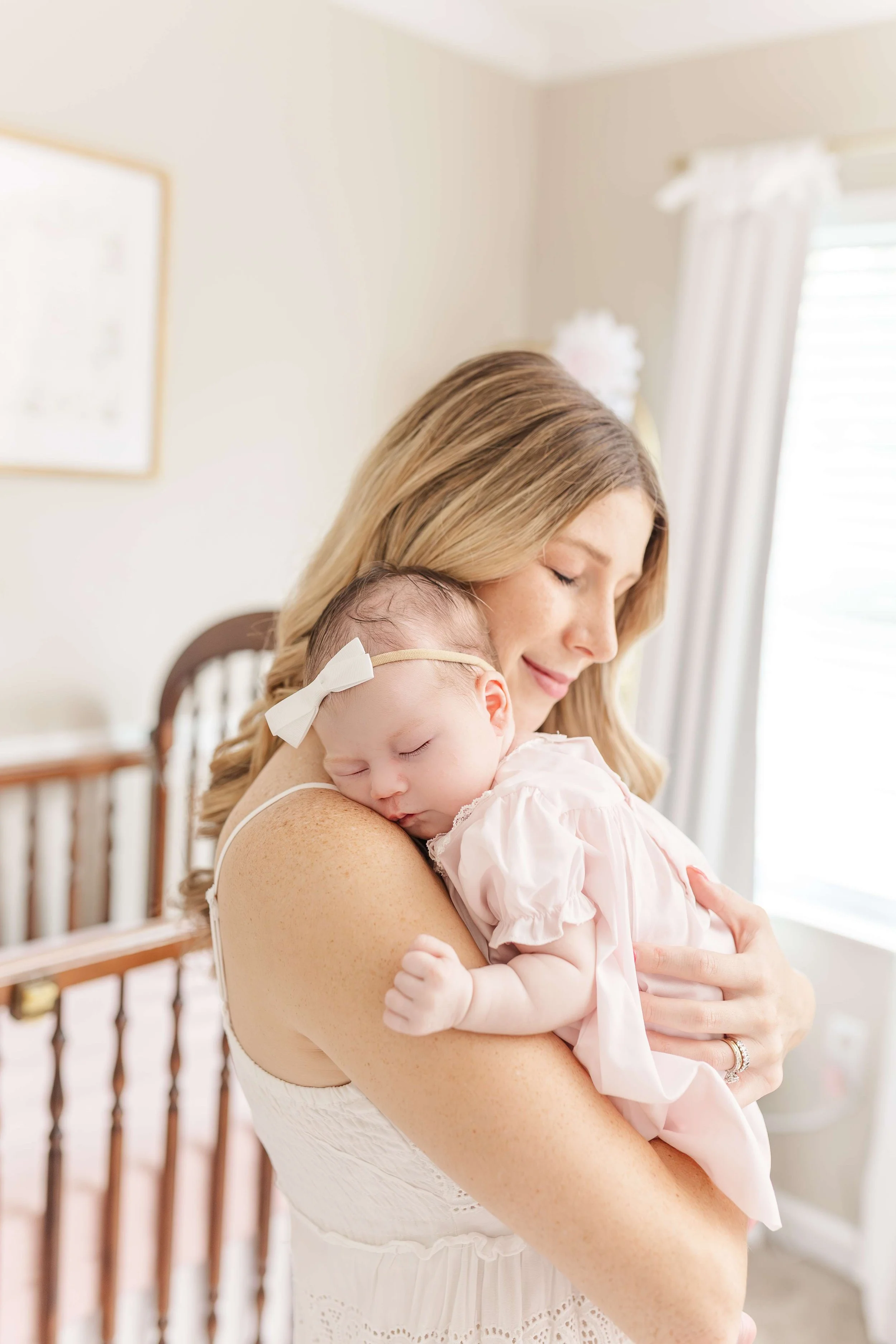Mother holding newborn in natural window light, lifestyle newborn photographer Greenville SC