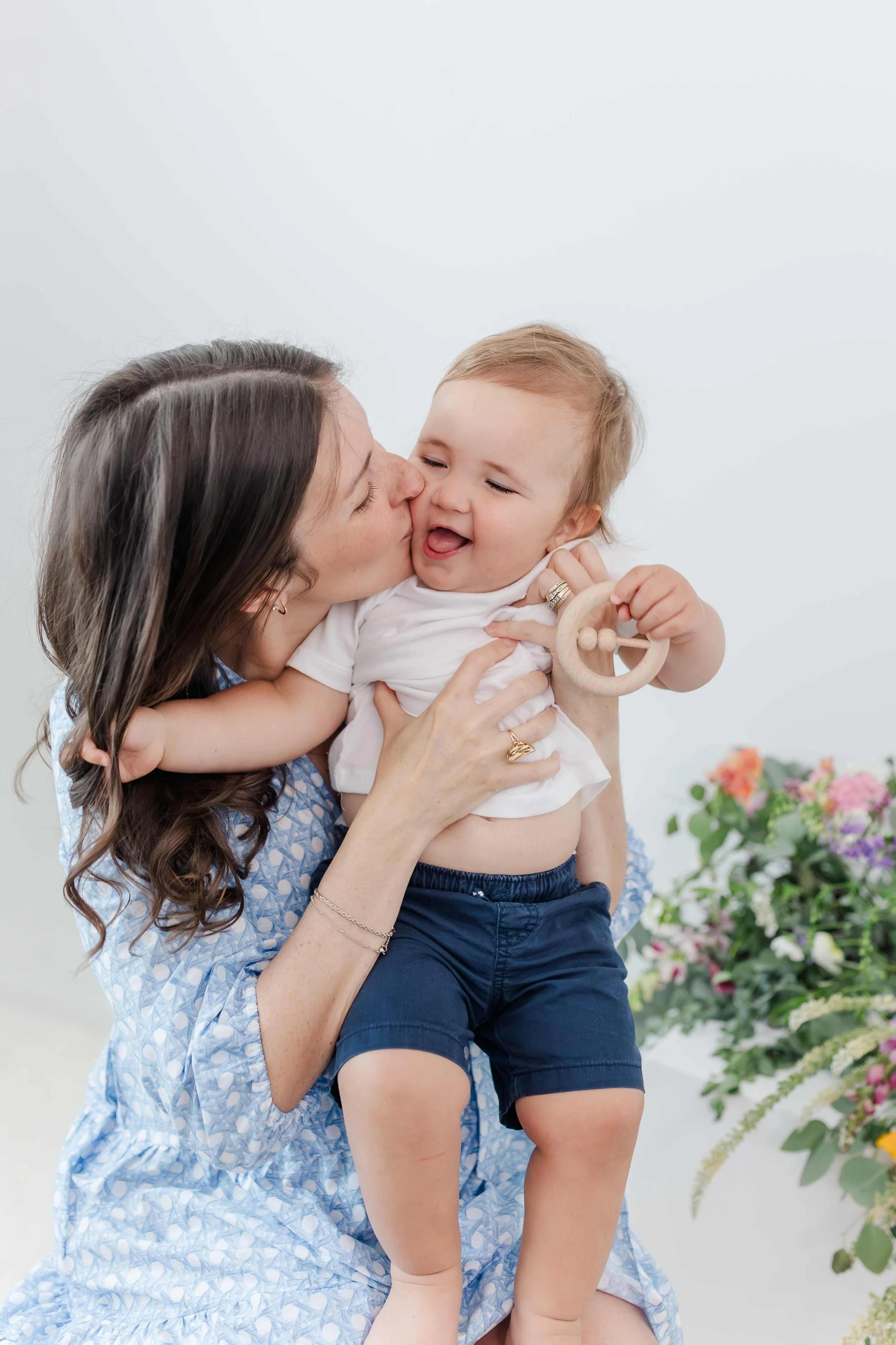 Mom kissing smiling toddler boy in studio during spring mommy and me session in Greenville SC