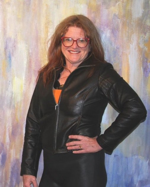 Carrie Howder, the artist, standing in front of a large abstract mural.