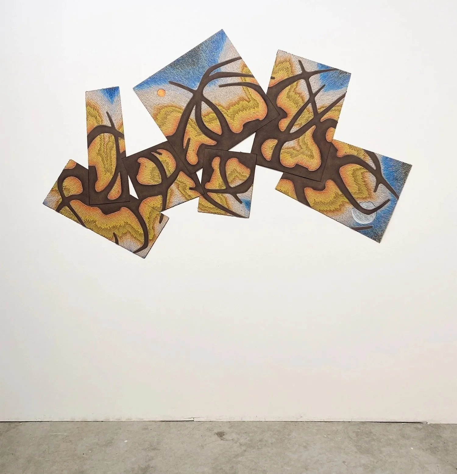 wall art installation with colorful carved panels connected by dark sculptural elements, displaying vibrant, swirling patterns in yellow, blue, and orange.