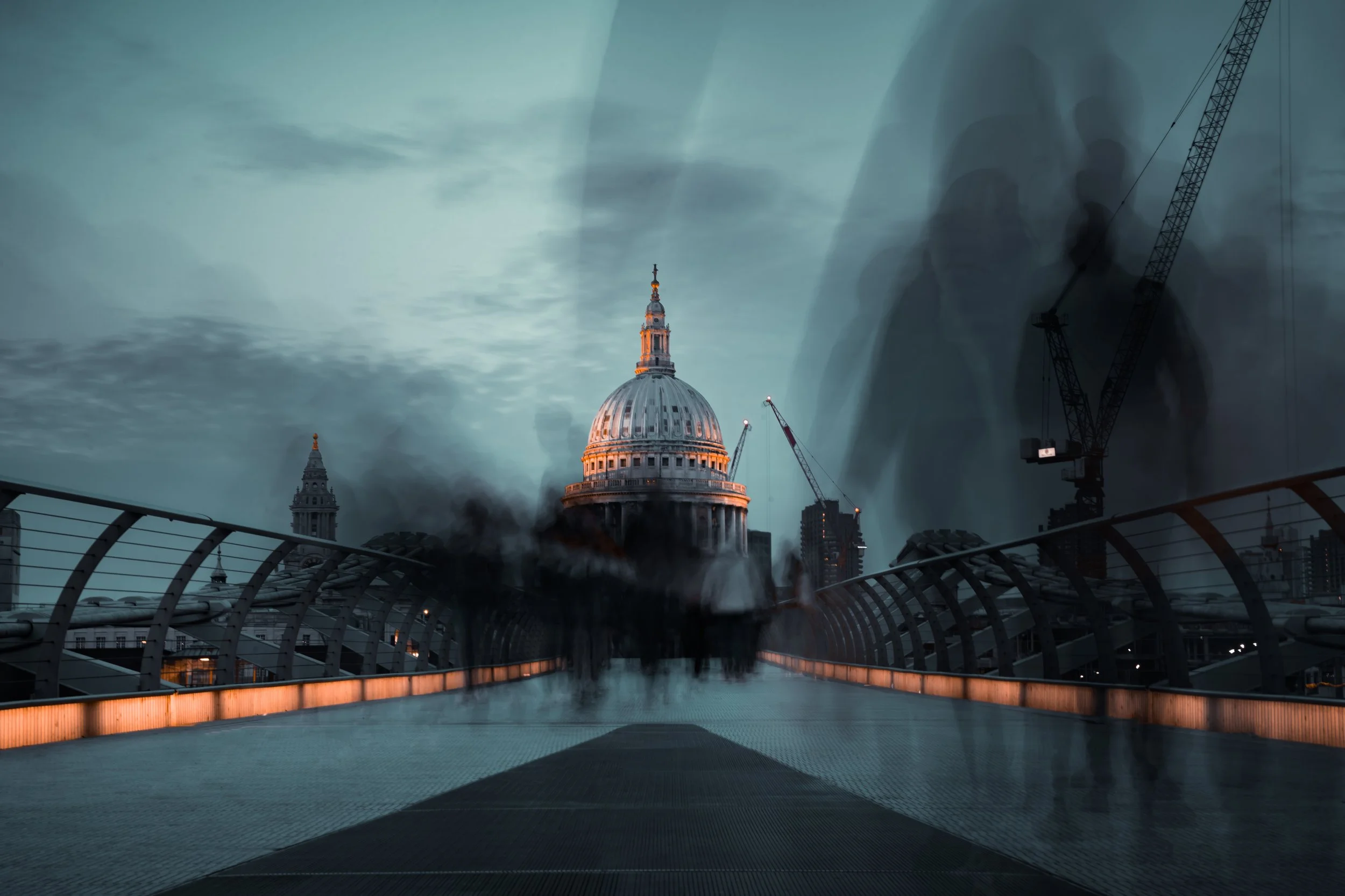 St. Paul's Cathedral and Millennium Bridge in London, with blurred motion of people and cranes in the background.