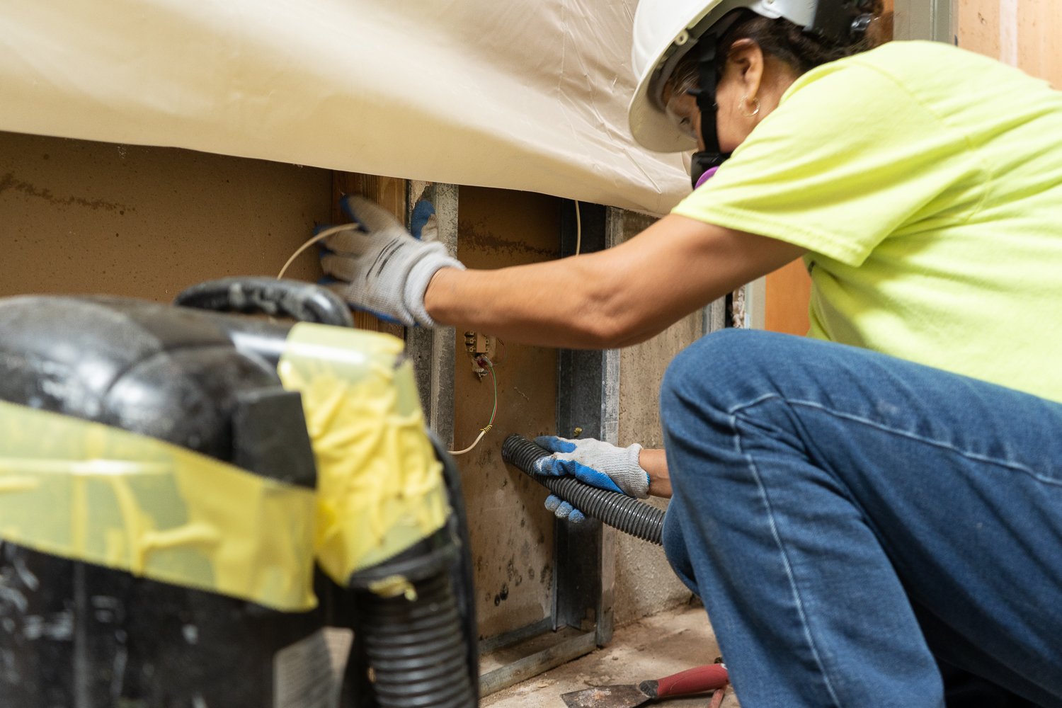 A worker uses a HEPA filtered vacuum to remove dangerous mold