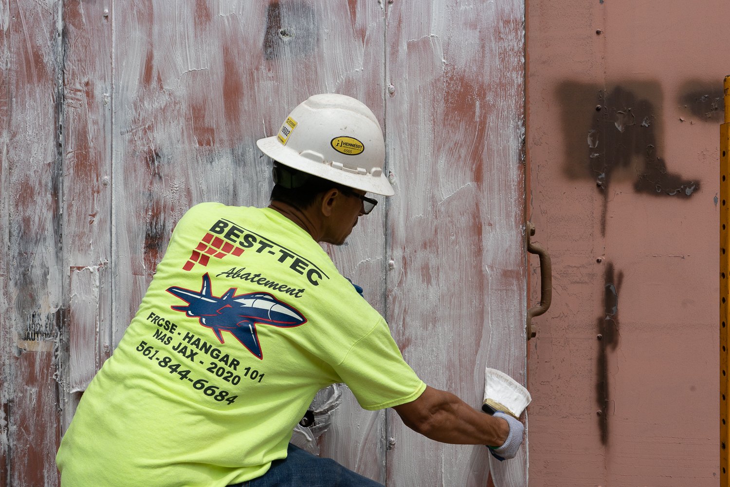 A worker applies a thick coat of paint stripper over paint that has tested positive for lead.