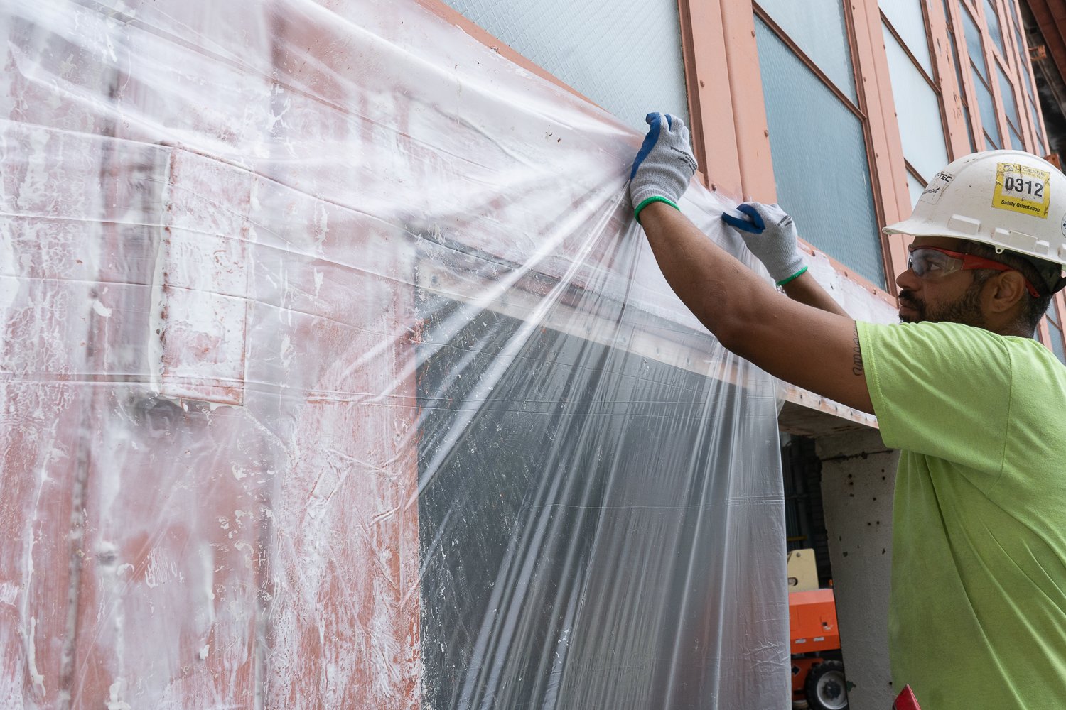 A work covers up paint stripper so that it remains moisture-laden and protected from the elements while it loosens up the paint.