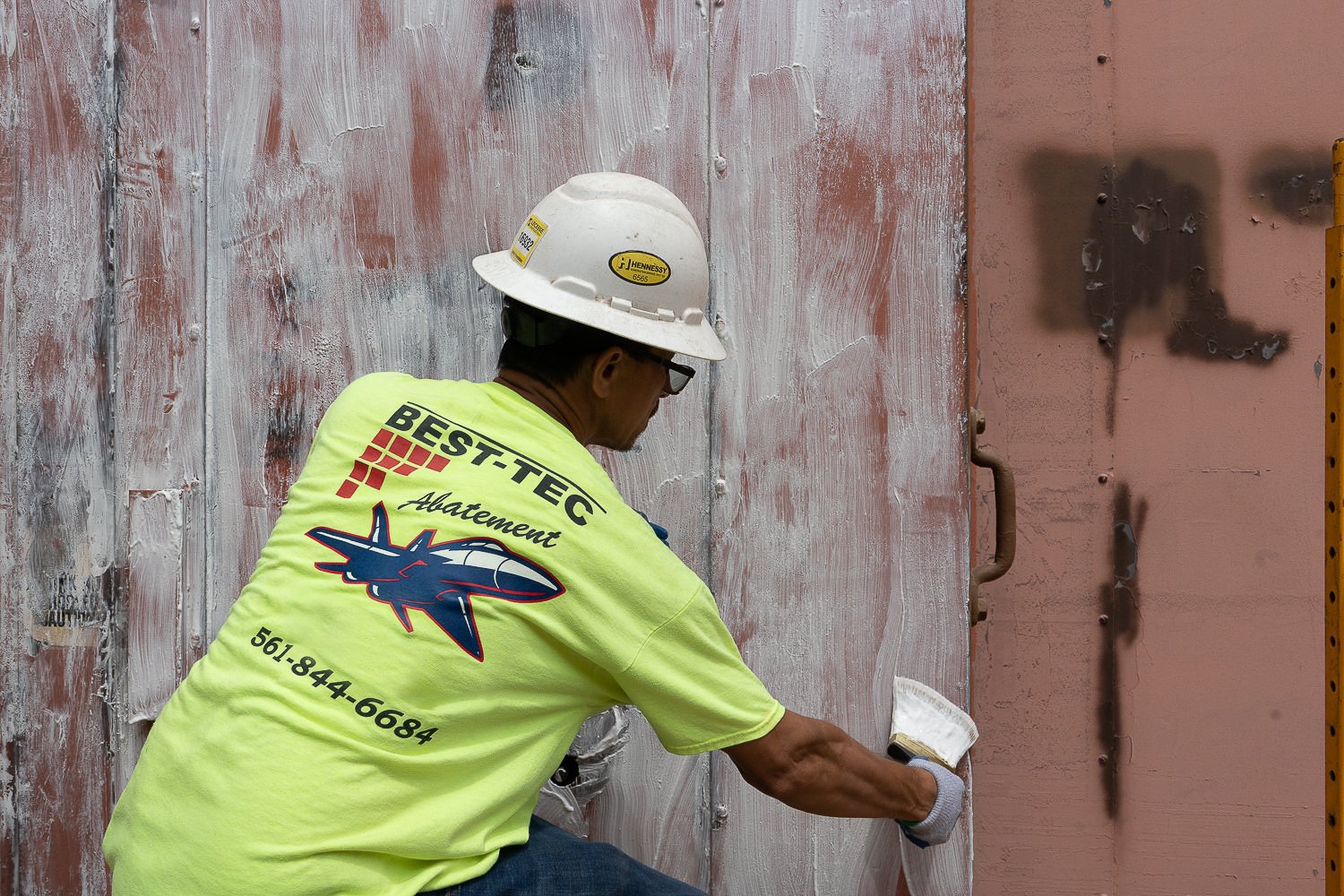 A worker applies paint stripper to remove lead paint. 