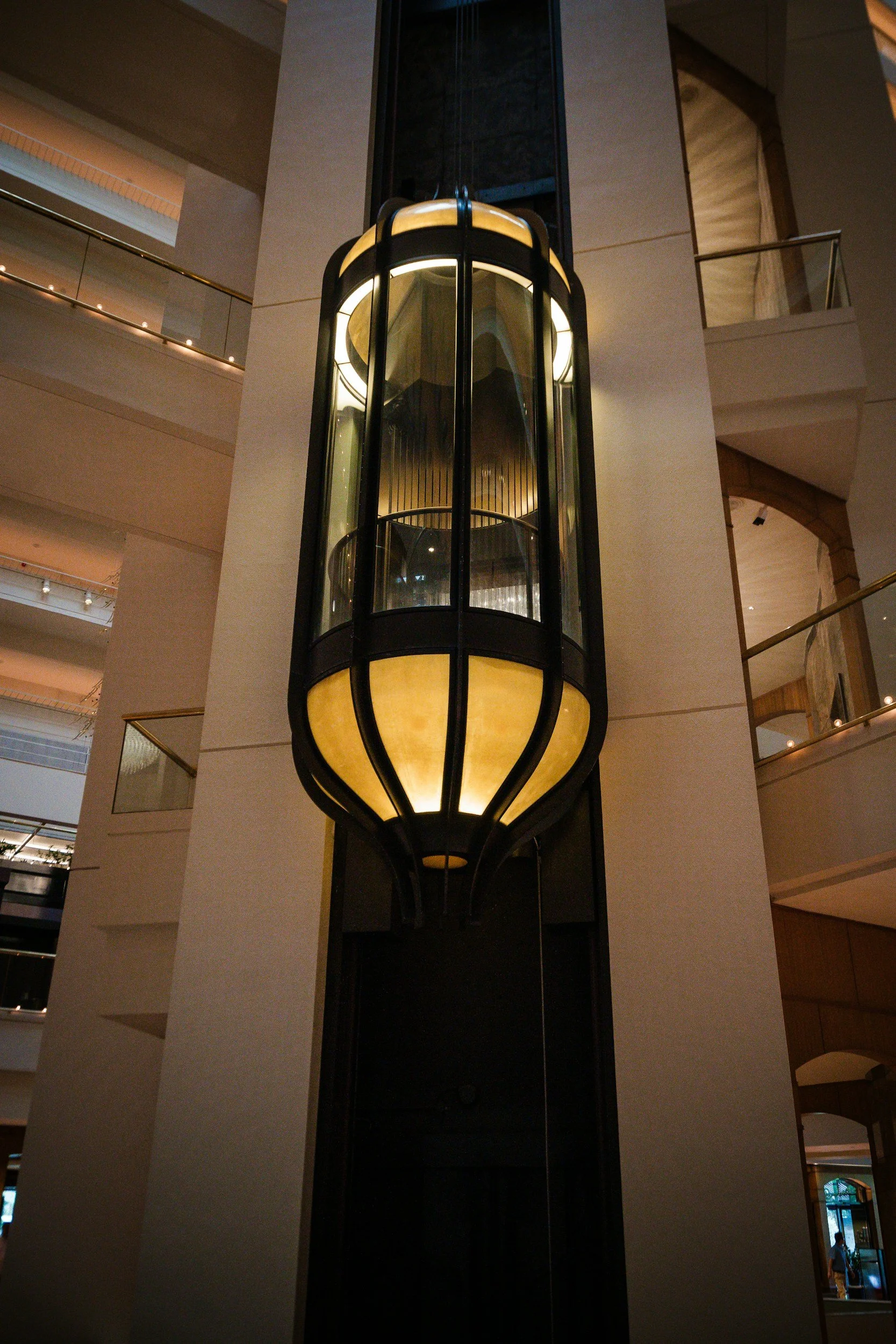 A large, decorative elevator with a glass and metal design inside a modern hotel lobby.